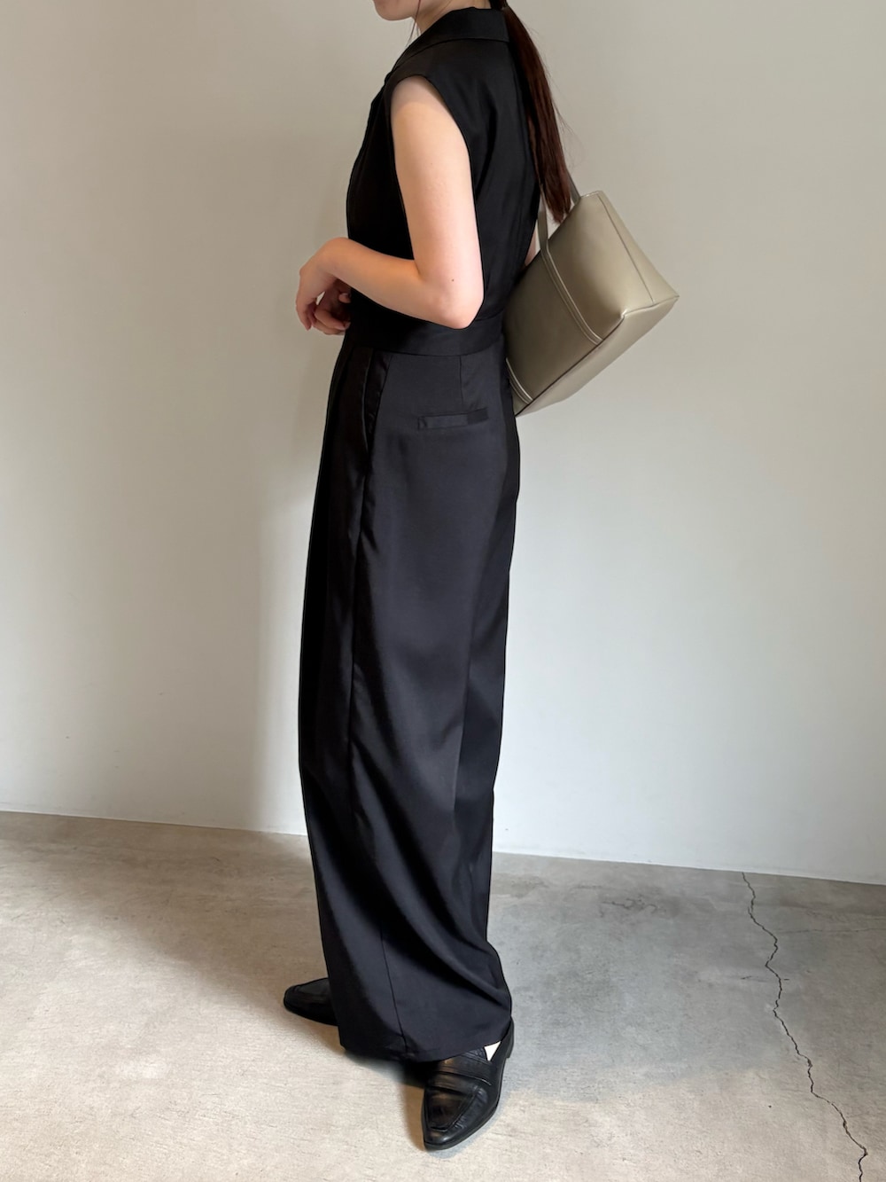 ベージュ系のショルダーバッグ、ホワイト系のキャミソール、ブラック系のパンツドレスを着用したレディースの春コーディネートの3枚目の写真