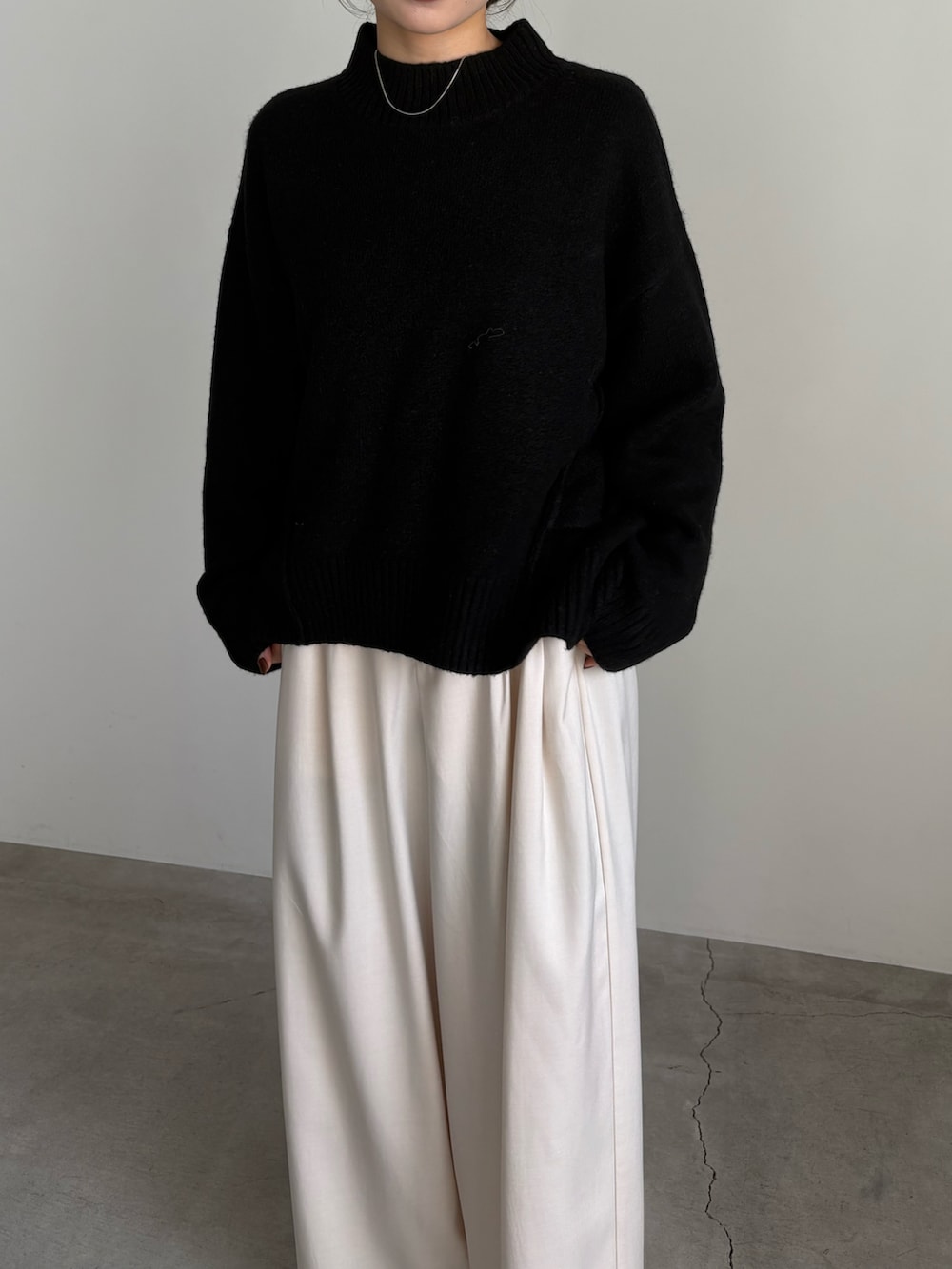 ブラック系のニット/セーター、ホワイト系のスラックスを着用したレディースの秋コーディネートの2枚目の写真