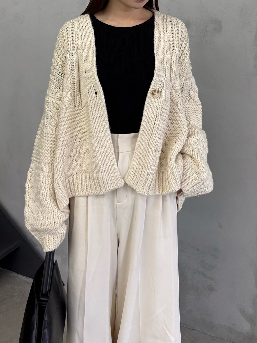 ホワイト系のカーディガン/ボレロ、ホワイト系のスラックス、ブラック系のハンドバッグを着用したレディースの秋コーディネートの4枚目の写真