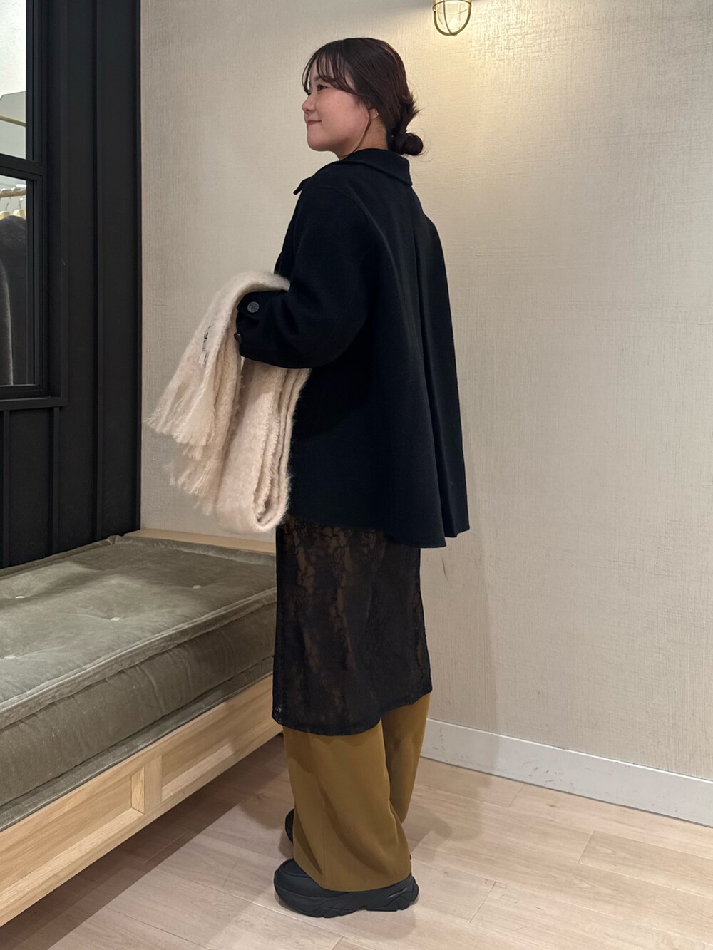 ブラック系のスカート、ホワイト系のカーディガン/ボレロ、ブラック系のピーコートを着用したレディースの冬コーディネートの3枚目の写真