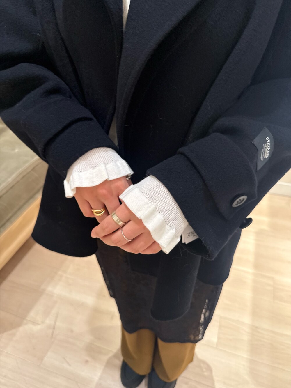 ブラック系のスカート、ホワイト系のカーディガン/ボレロ、ブラック系のピーコートを着用したレディースの冬コーディネートの5枚目の写真