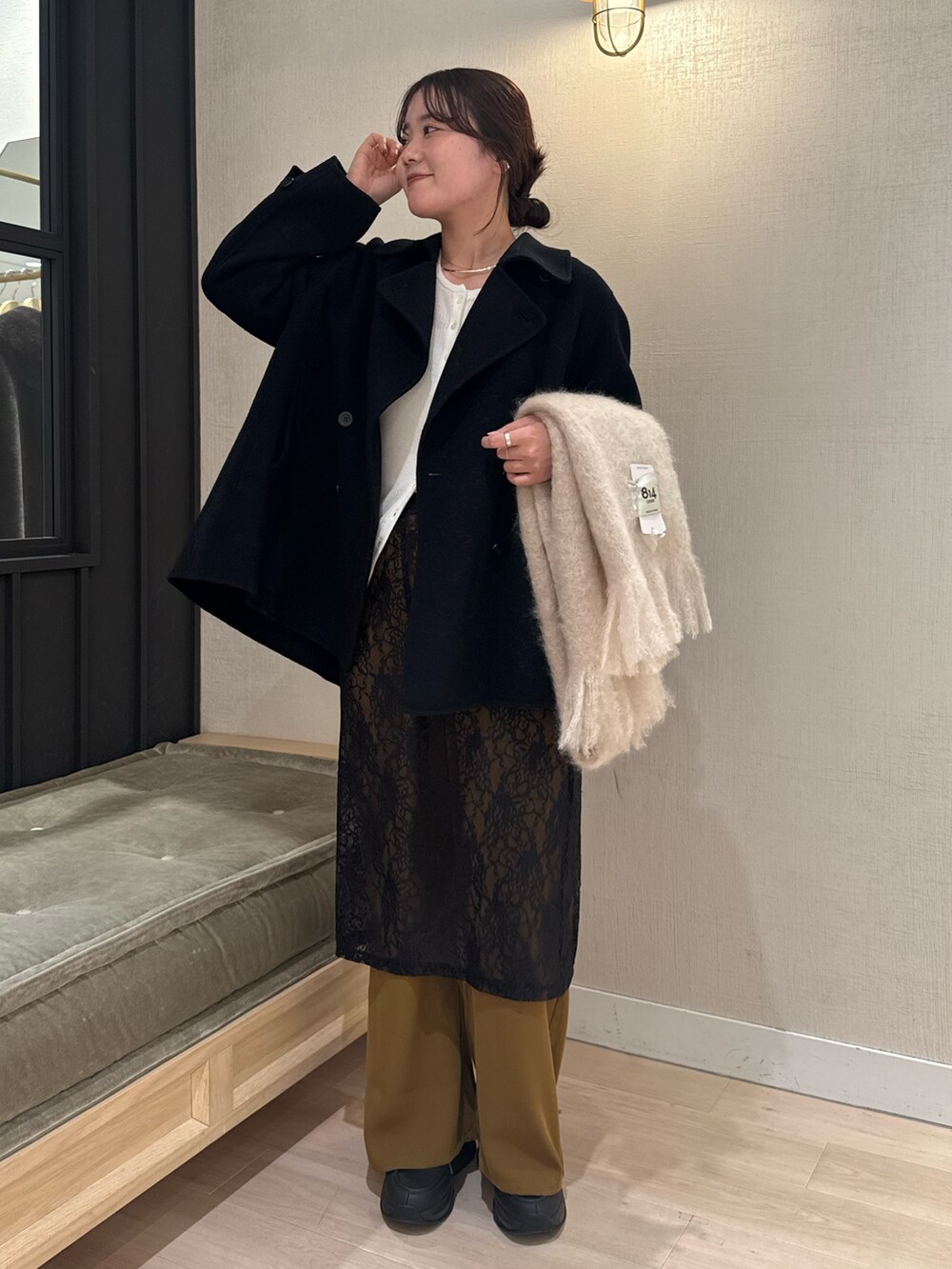 ブラック系のスカート、ホワイト系のカーディガン/ボレロ、ブラック系のピーコートを着用したレディースの冬コーディネートの2枚目の写真