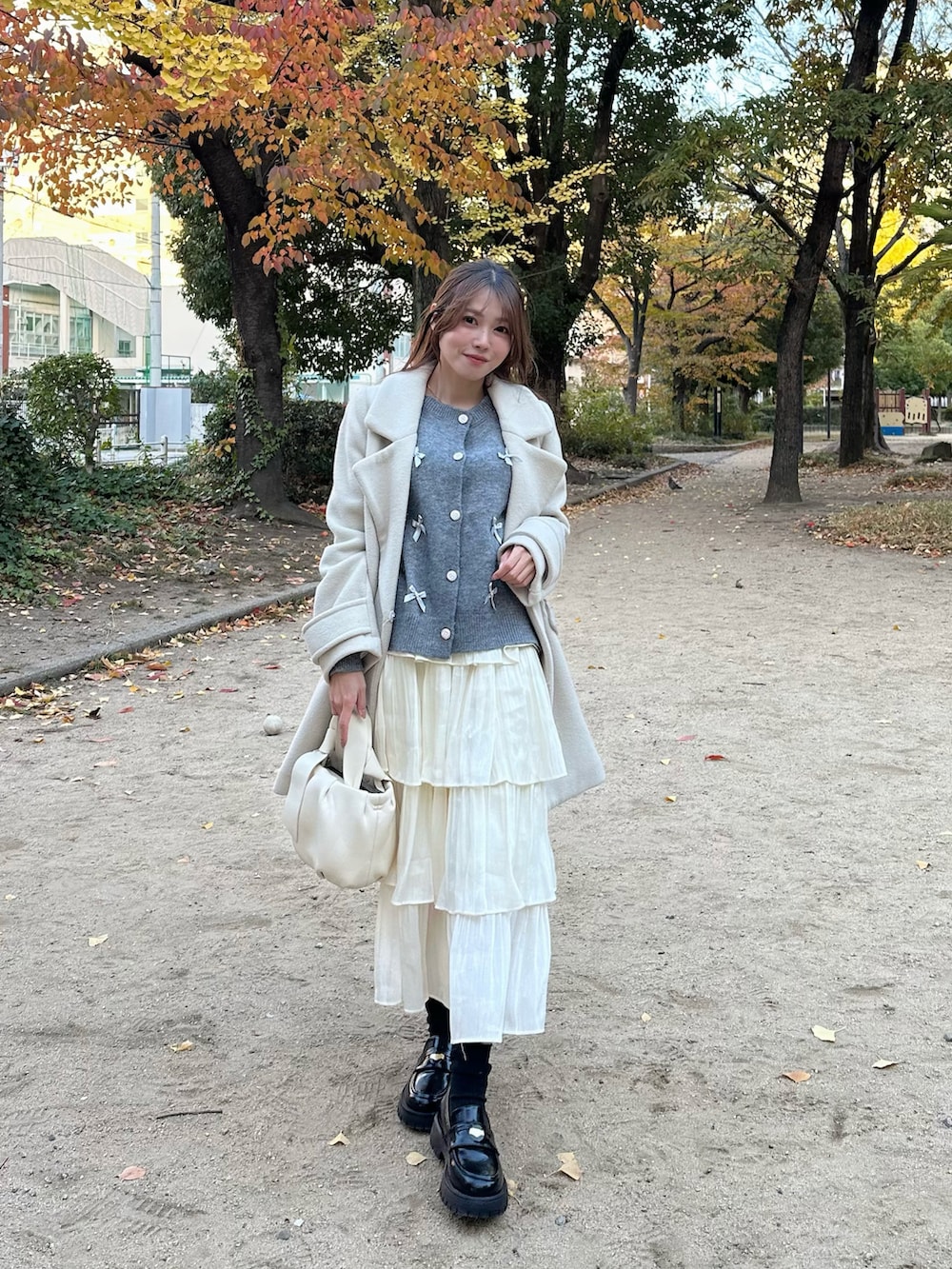 ホワイト系のショルダーバッグ、ブラック系のローファーを着用したレディースの秋コーディネートの2枚目の写真