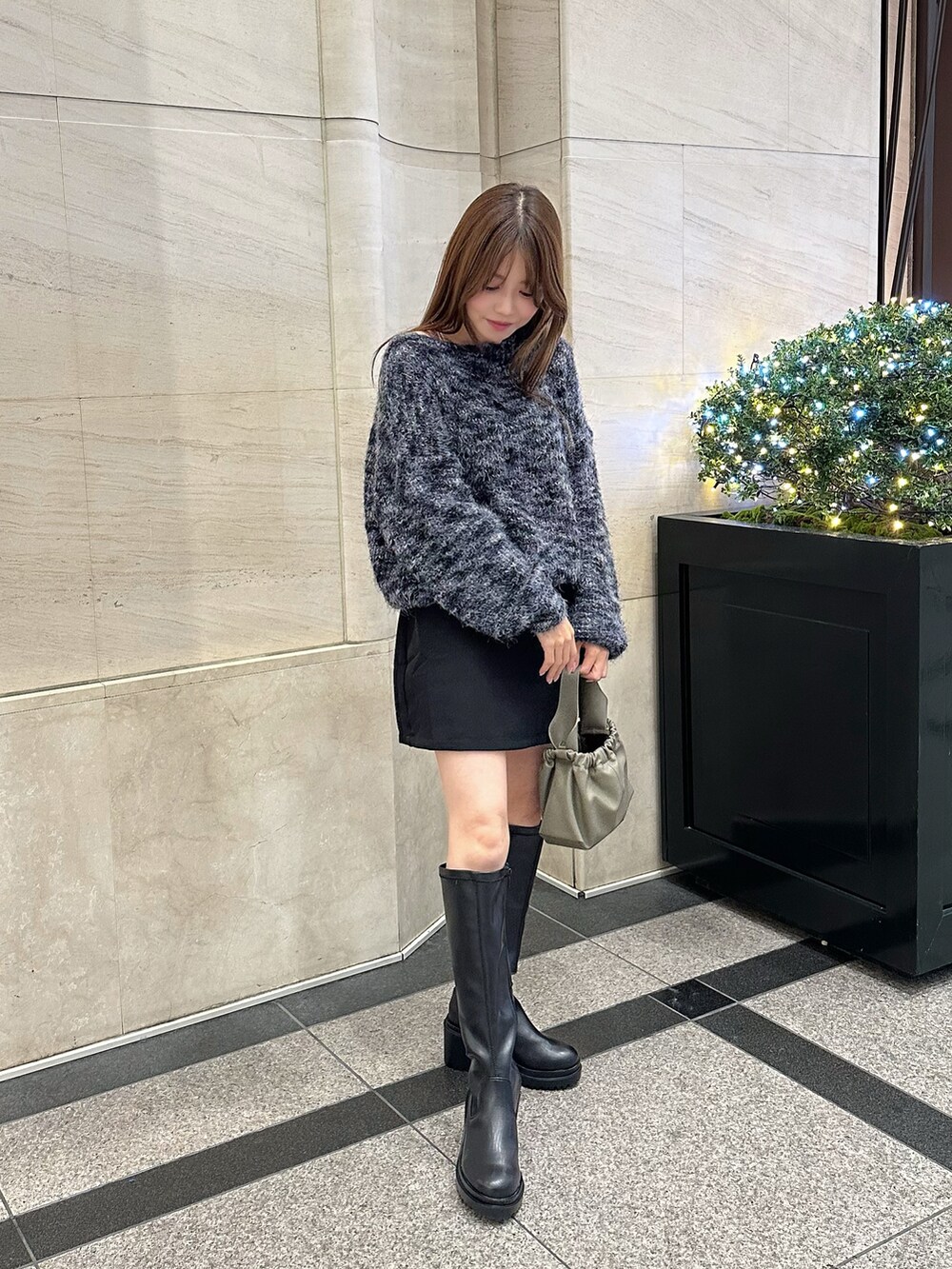 ベージュ系のショルダーバッグ、ブラック系のブーツ、ブラック系のスカートを着用したレディースの秋コーディネートの2枚目の写真