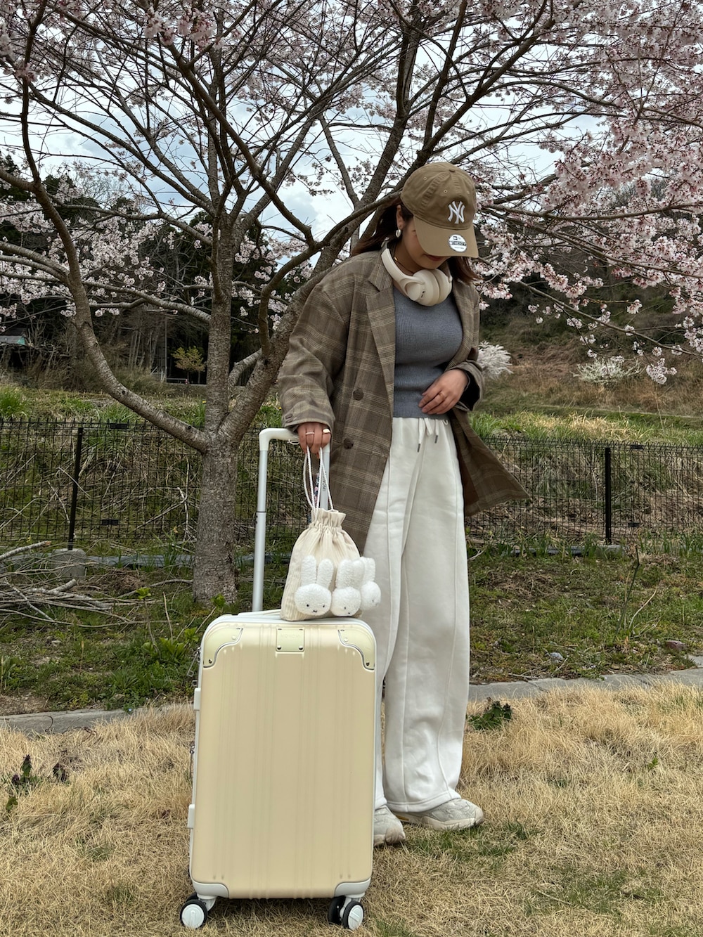 グレー系のTシャツ/カットソー、ホワイト系のショルダーバッグ、イエロー系のスーツケース/キャリーバッグを着用したレディースの春コーディネートの2枚目の写真