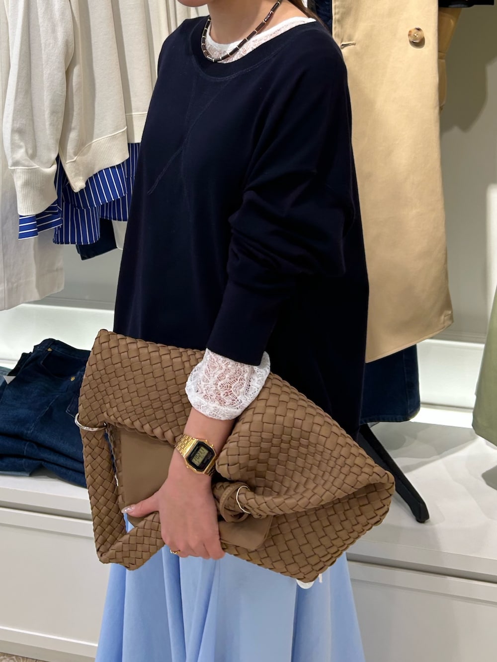 ブルー系のスカート、ブラウン系のショルダーバッグ、ブルー系のニット/セーターを着用したレディースの春コーディネートの2枚目の写真