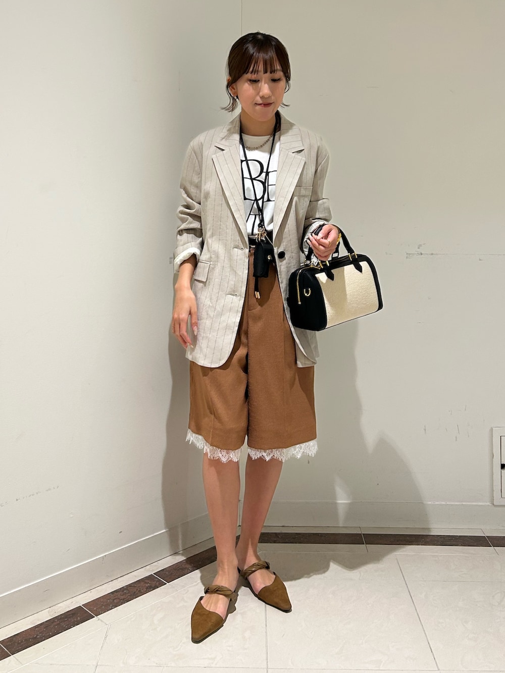 ブラック系のボストンバッグ、イエロー系のその他パンツ、ホワイト系のTシャツ/カットソーを着用したレディースの春コーディネートの2枚目の写真