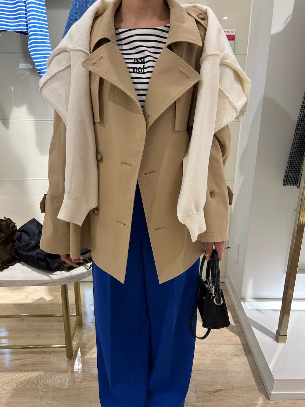 ベージュ系のブルゾン、ブラック系のショルダーバッグ、ホワイト系のTシャツ/カットソーを着用したレディースの冬コーディネートの2枚目の写真