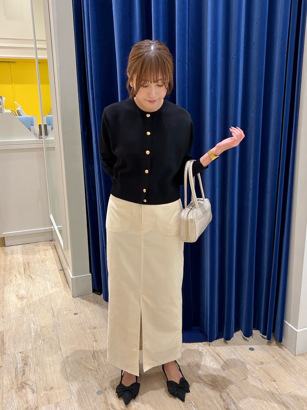 ブラック系のカーディガン/ボレロ、ホワイト系のボストンバッグ、ホワイト系のスカートを着用したレディースの秋コーディネートの3枚目の写真