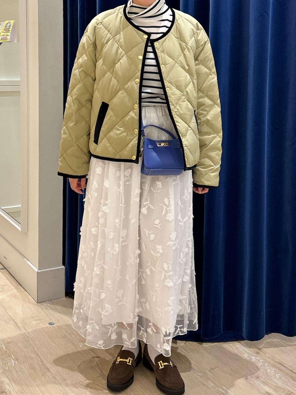 ベージュ系のダウンジャケット/コート、ホワイト系のニット/セーター、ブルー系のショルダーバッグを着用したレディースの秋コーディネートの2枚目の写真