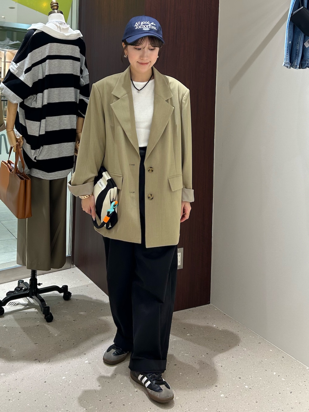 ベージュ系のテーラードジャケット、ブラック系のボディバッグ/ウエストポーチ、ホワイト系のタンクトップを着用したレディースの春コーディネートの2枚目の写真