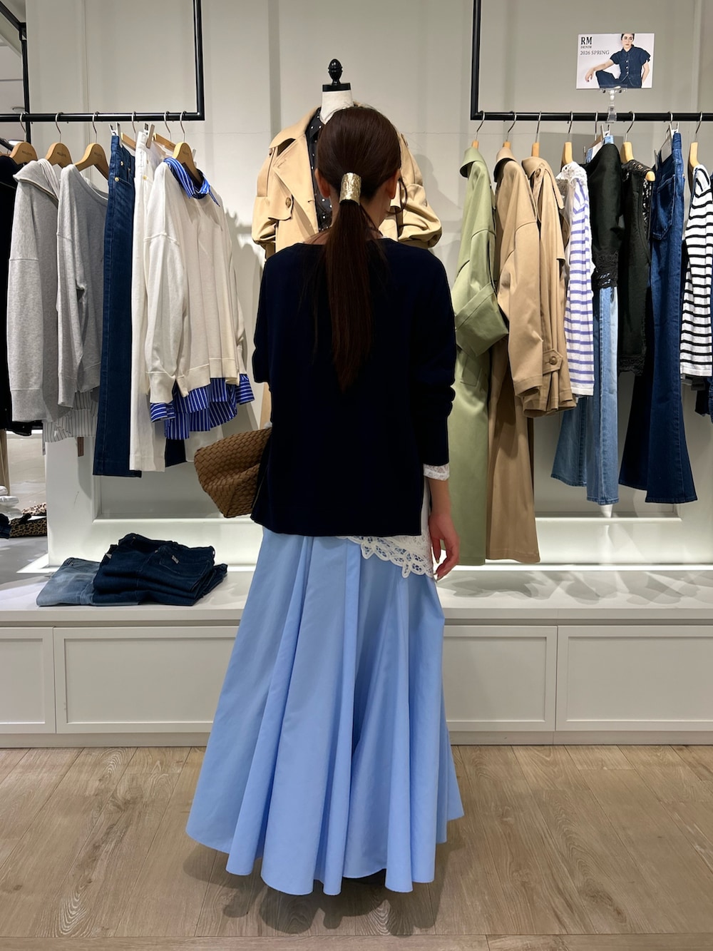 ブルー系のスカート、ブラウン系のショルダーバッグ、ブルー系のニット/セーターを着用したレディースの春コーディネートの5枚目の写真