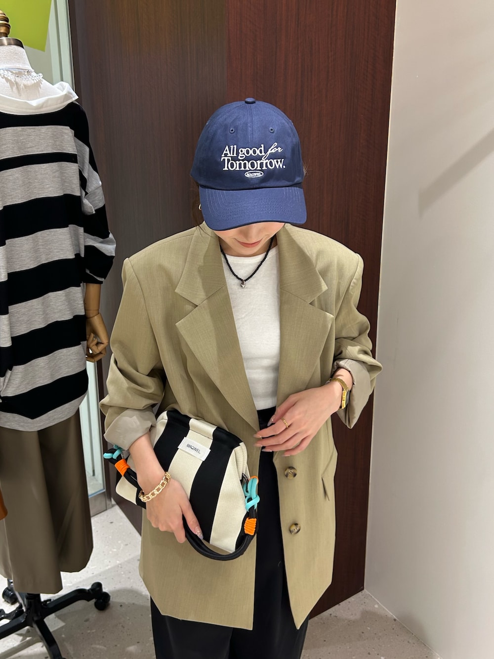 ベージュ系のテーラードジャケット、ブラック系のボディバッグ/ウエストポーチ、ホワイト系のタンクトップを着用したレディースの春コーディネートの3枚目の写真