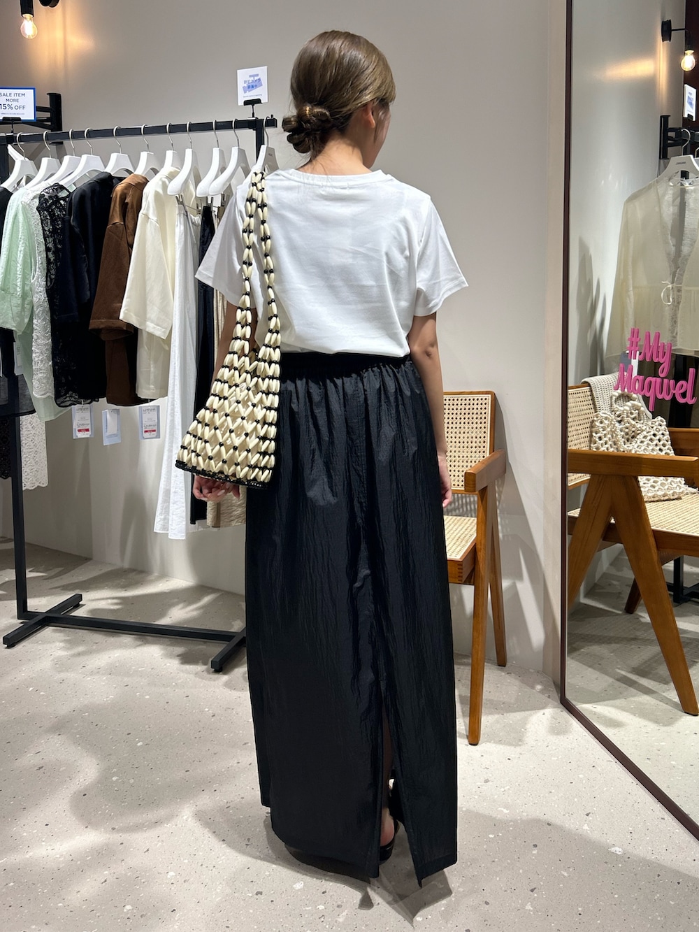 ブラック系のスカート、ホワイト系のTシャツ/カットソーを着用したレディースの夏コーディネートの2枚目の写真