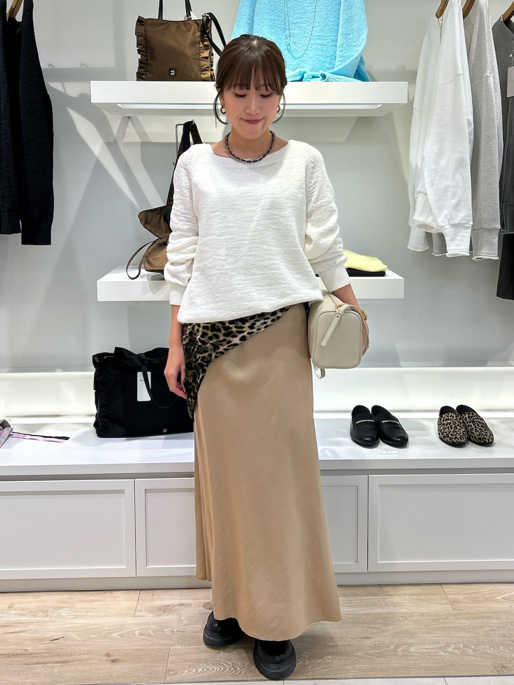 ホワイト系のニット/セーター、ホワイト系のショルダーバッグ、ベージュ系のスカートを着用したレディースの冬コーディネートの2枚目の写真