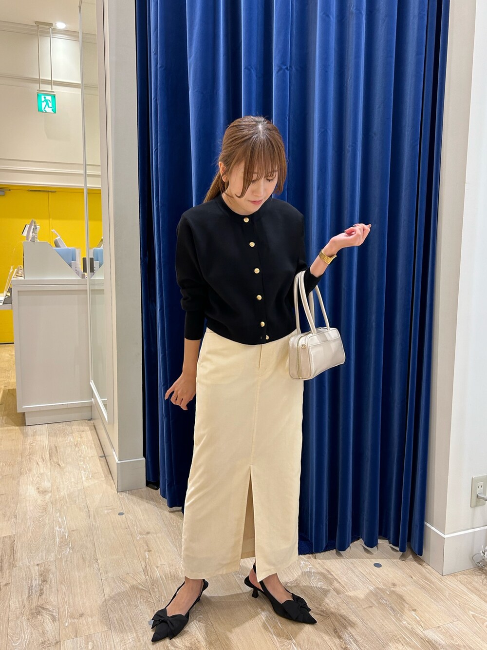 ブラック系のカーディガン/ボレロ、ホワイト系のボストンバッグ、ホワイト系のスカートを着用したレディースの秋コーディネートの4枚目の写真
