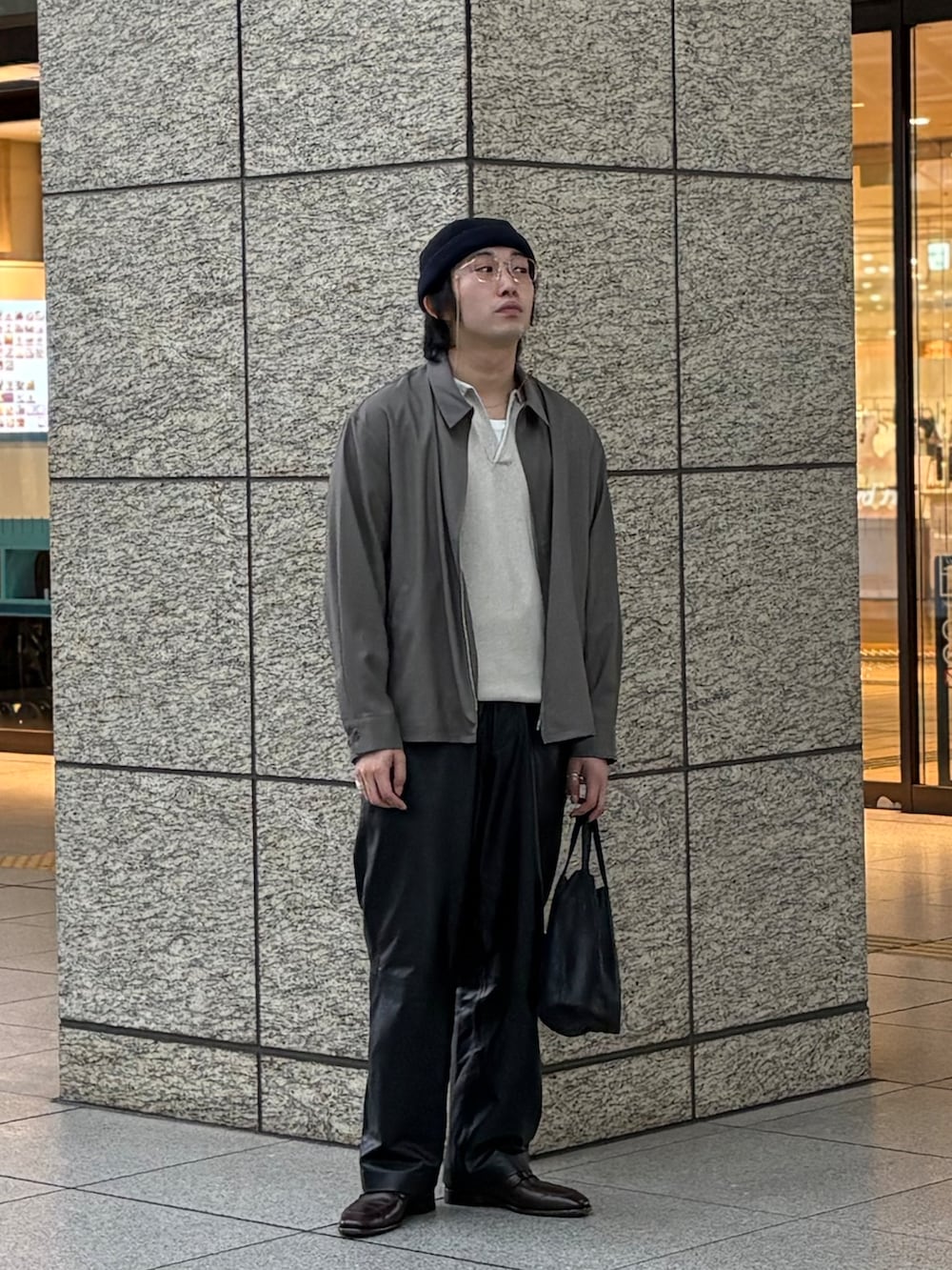 ホワイト系のポロシャツ、グレー系のブルゾン、ブラック系のショルダーバッグを着用したメンズの春コーディネートの2枚目の写真