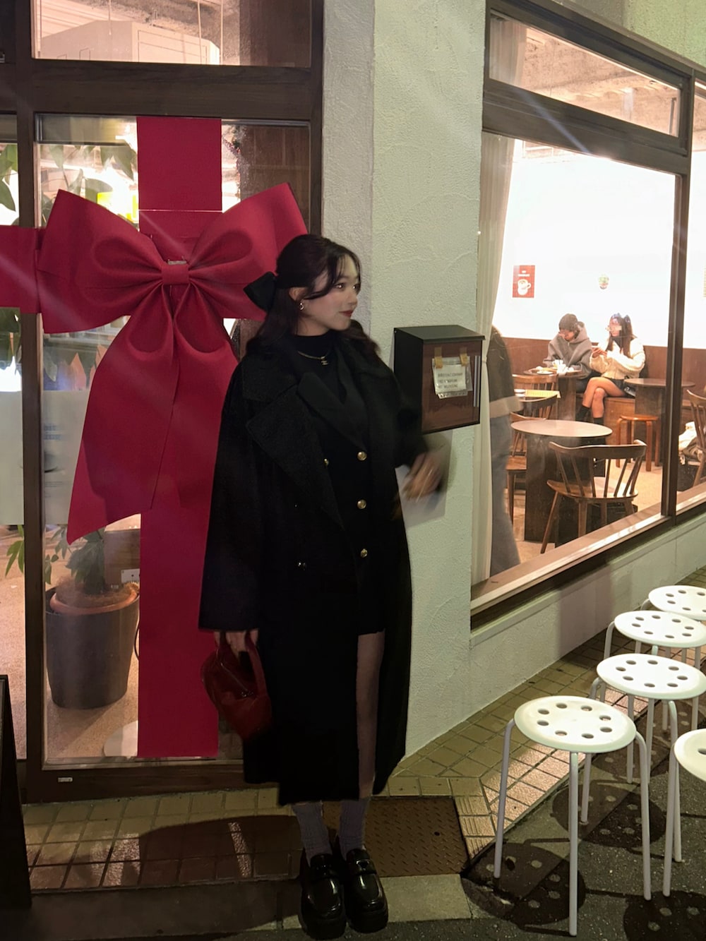 ブラック系のノーカラーコート、ブラック系のワンピース、レッド系のハンドバッグを着用したレディースの冬コーディネートの4枚目の写真