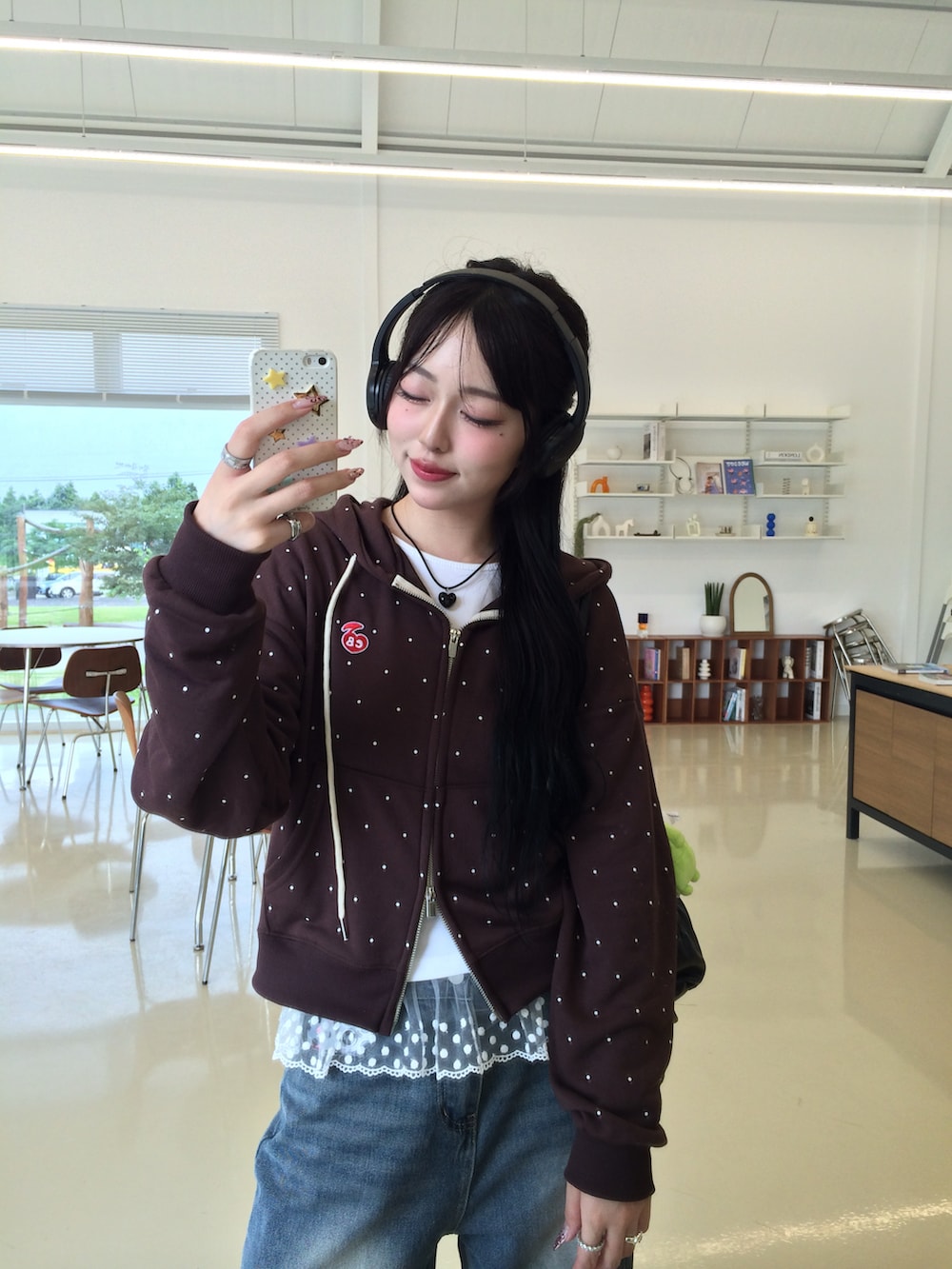 ブルー系のデニムパンツ、ブラウン系のパーカー、ブラック系のスニーカーを着用したレディースの秋コーディネートの3枚目の写真