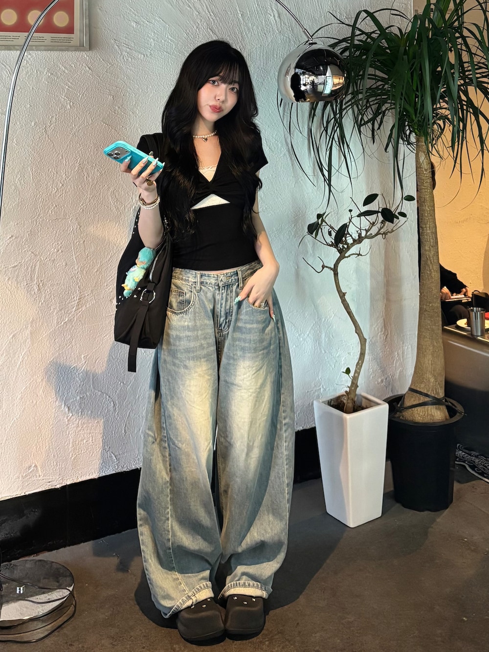 ブラック系のショルダーバッグ、ブルー系のデニムパンツ、ブラック系のサンダルを着用したレディースの夏コーディネートの2枚目の写真