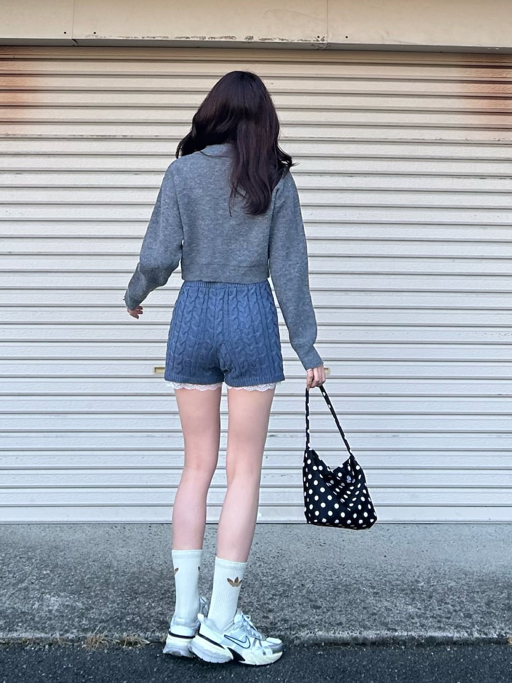 ブラック系のショルダーバッグ、ホワイト系のスニーカー、グレー系のニット/セーターを着用したレディースの冬コーディネートの3枚目の写真