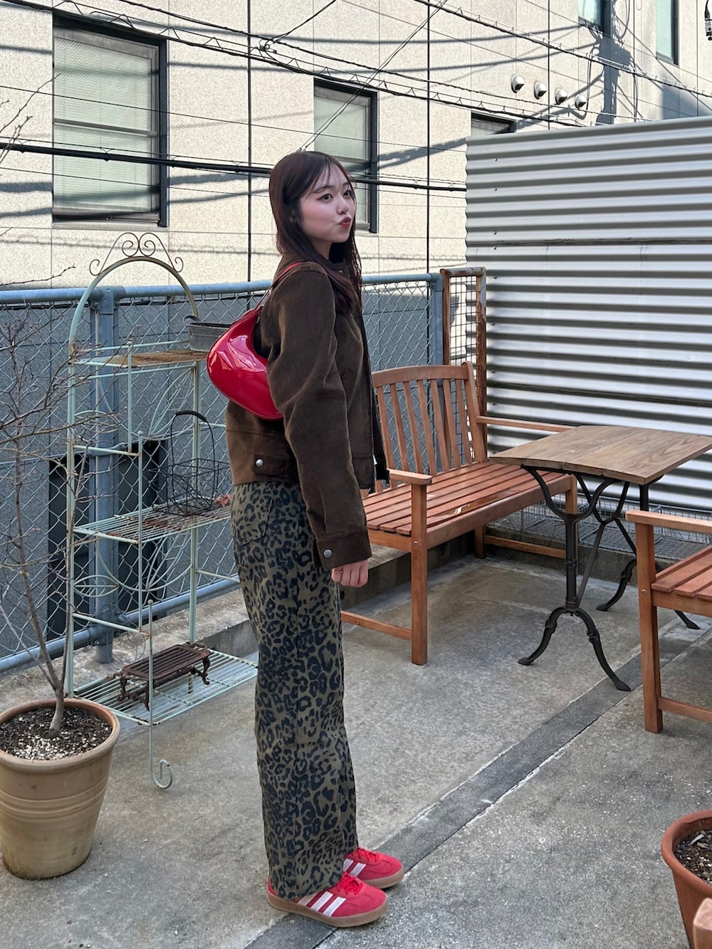 ブラウン系のデニムパンツ、レッド系のスニーカー、レッド系のハンドバッグを着用したレディースの春コーディネートの2枚目の写真