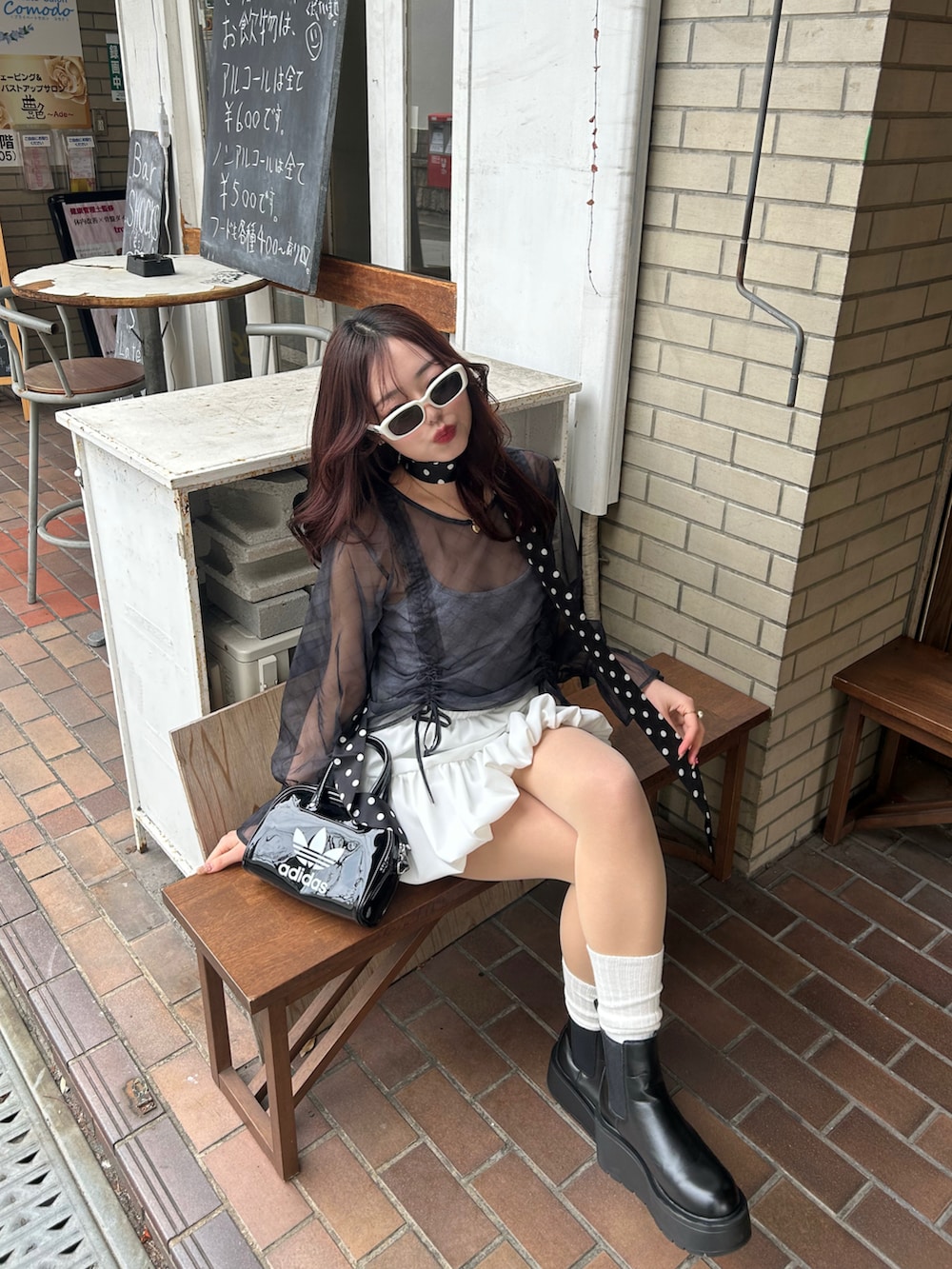 その他のハンドバッグ、ホワイト系のスカート、ブラック系のブーツを着用したレディースの春コーディネートの2枚目の写真