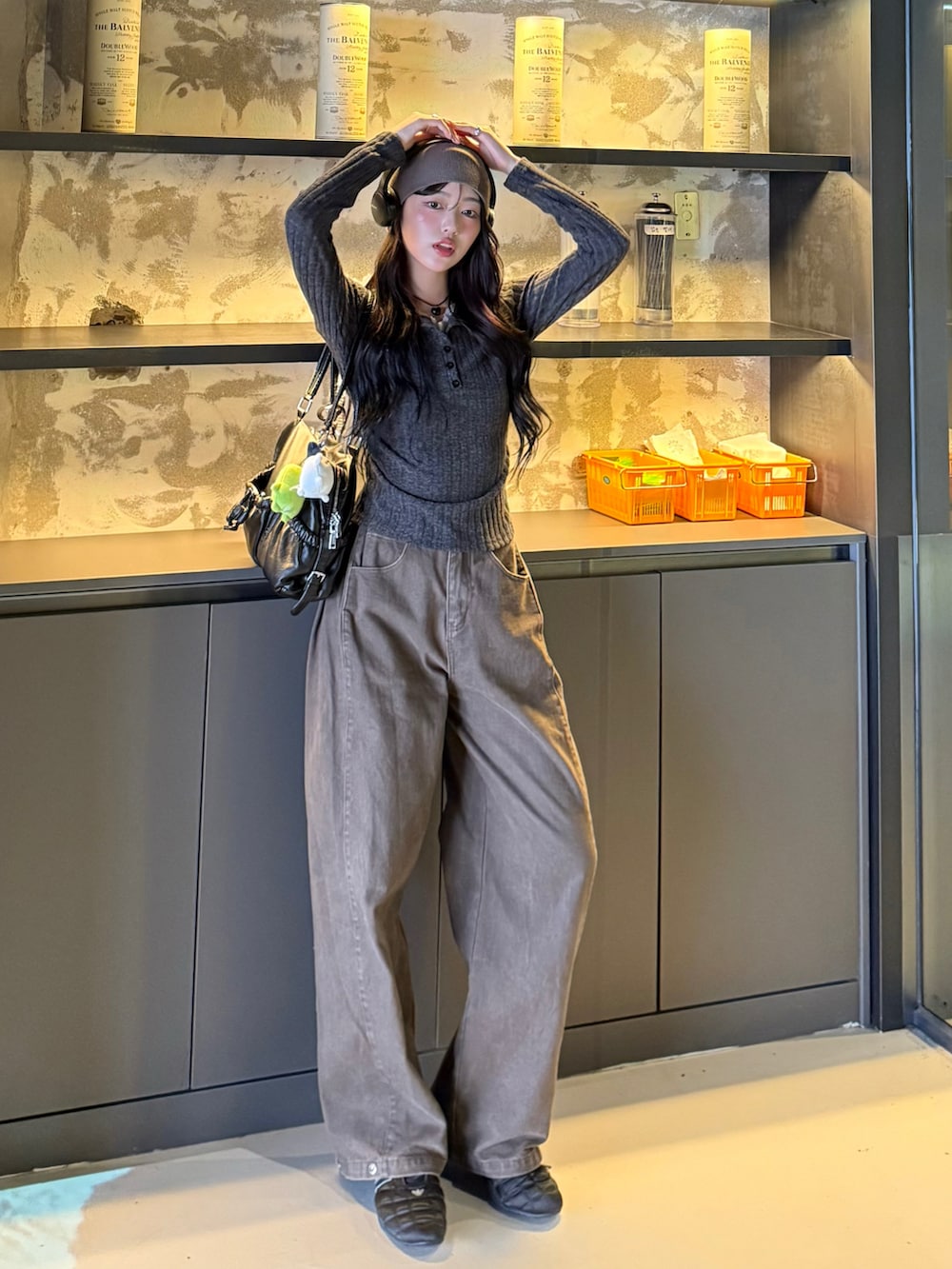 グレー系のニット/セーター、ブラウン系のデニムパンツ、ブラック系のスニーカーを着用したレディースの秋コーディネートの2枚目の写真