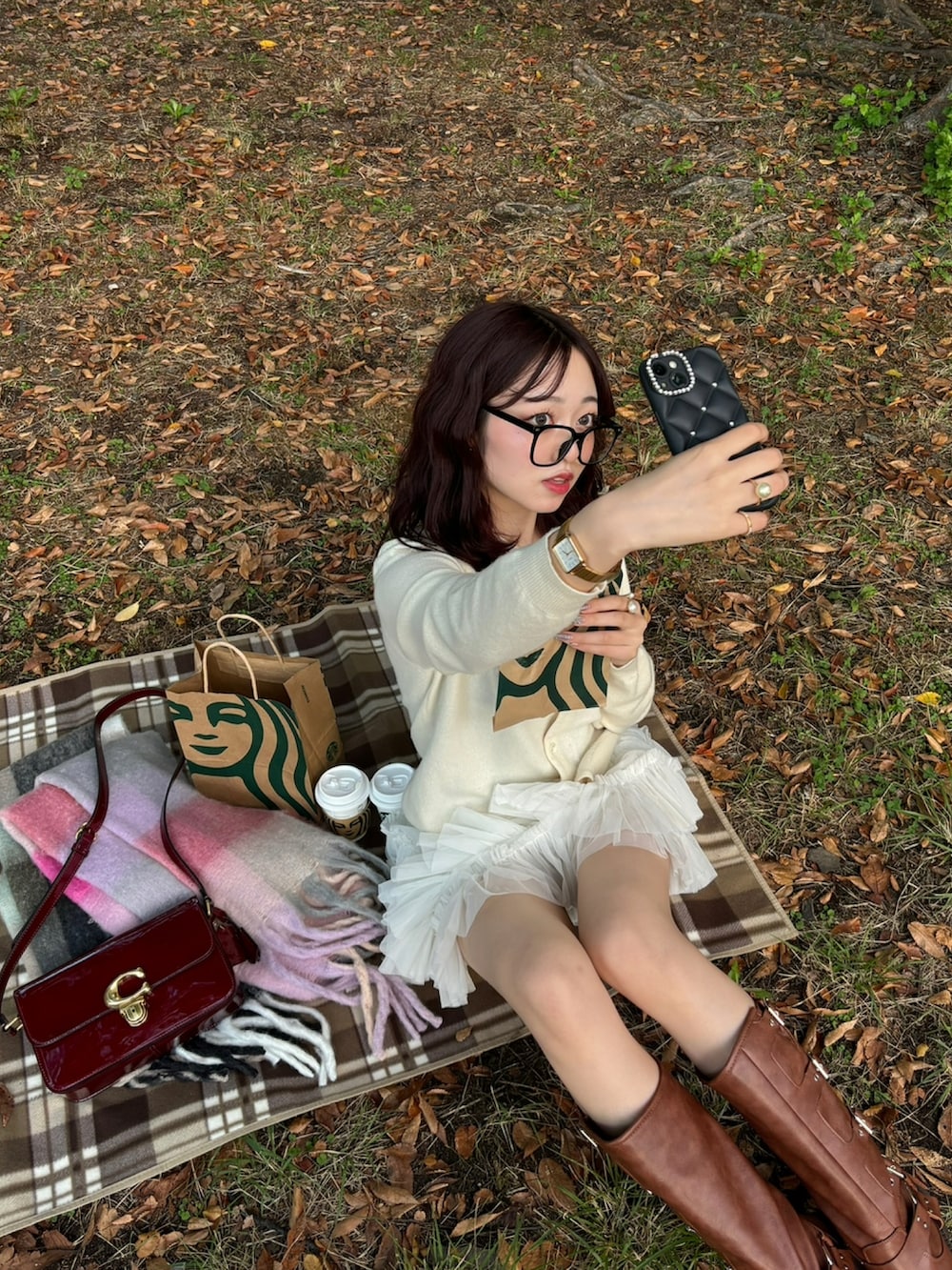 ホワイト系のカーディガン/ボレロ、レッド系のショルダーバッグ、ブラウン系のブーツを着用したレディースの冬コーディネートの2枚目の写真