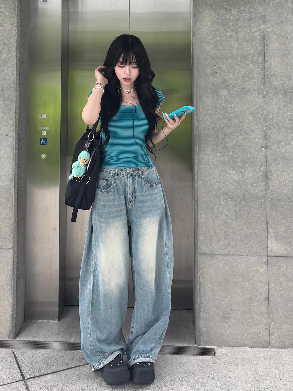 ブルー系のデニムパンツ、ブラック系のショルダーバッグ、ブラック系のサンダルを着用したレディースの夏コーディネートの2枚目の写真