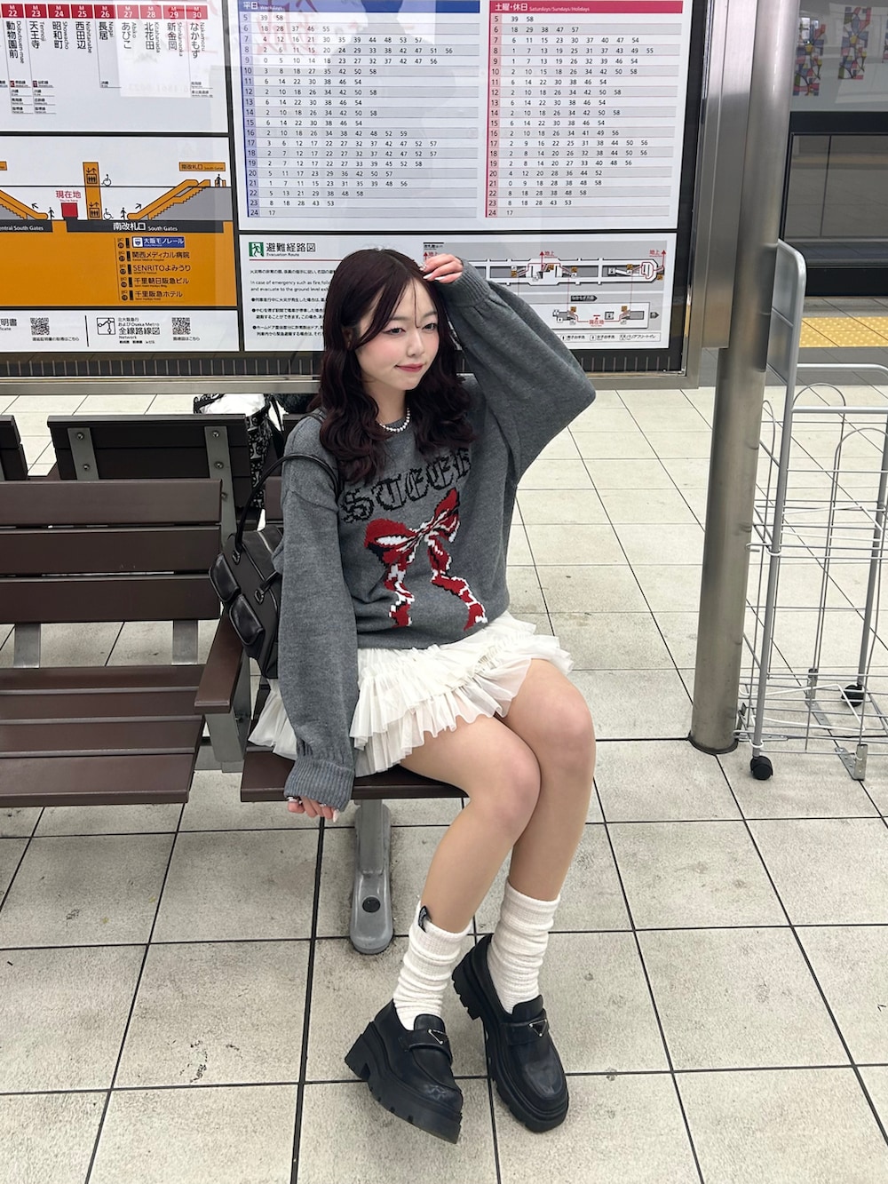 グレー系のニット/セーター、ホワイト系のスカート、ブラウン系のハンドバッグを着用したレディースの冬コーディネートの3枚目の写真