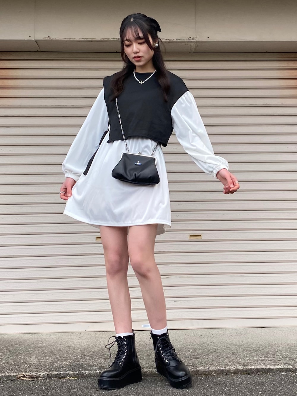 ホワイト系のワンピース、ブラック系のショルダーバッグ、ブラック系のブーツを着用したレディースの冬コーディネートの3枚目の写真