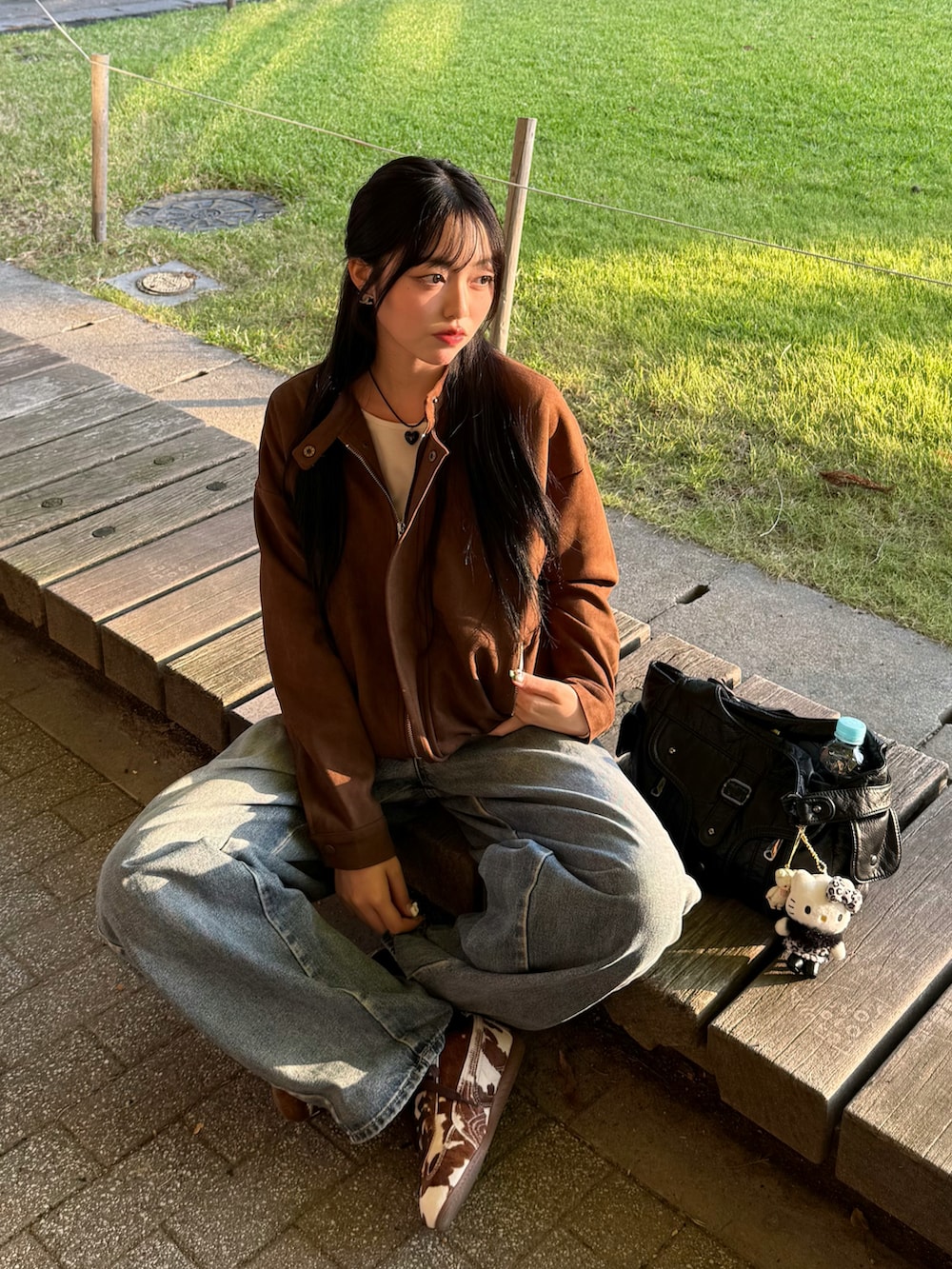 ブラウン系のスニーカー、ブラウン系のライダースジャケット、ブルー系のデニムパンツを着用したレディースの秋コーディネートの4枚目の写真