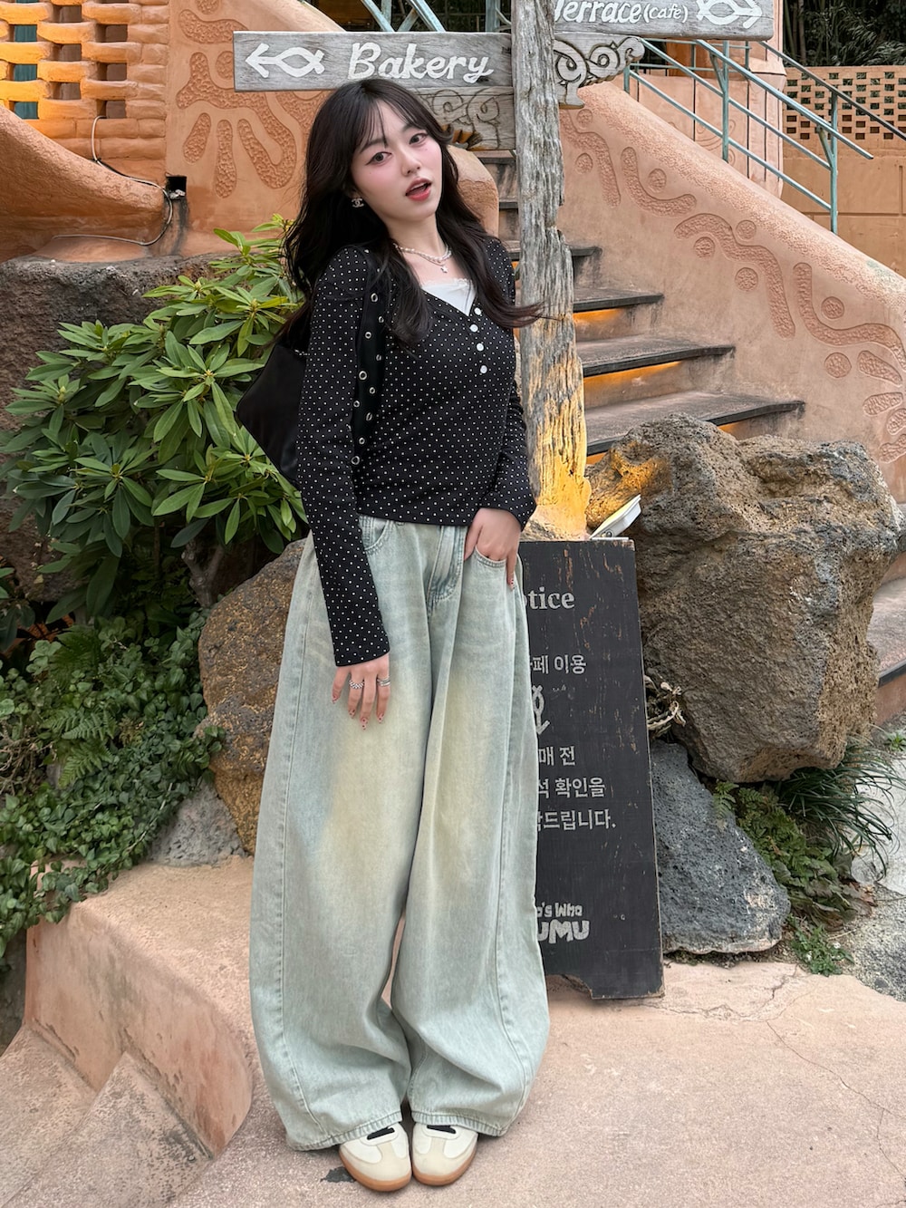 ブルー系のデニムパンツ、ブラック系のTシャツ/カットソー、ブラック系のハンドバッグを着用したレディースの春コーディネートの2枚目の写真