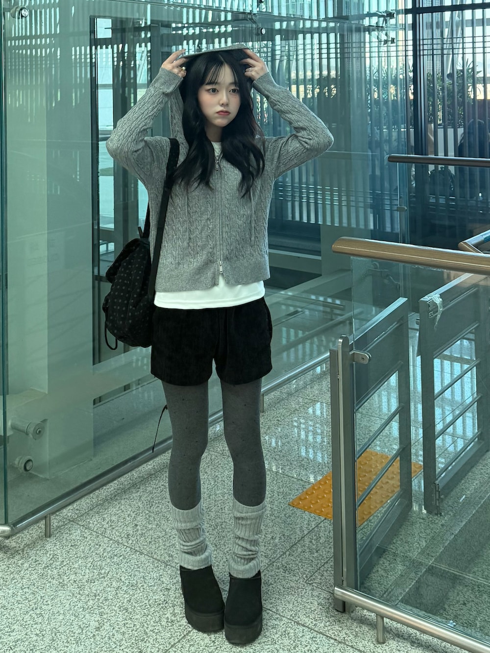 ブラック系のブーツ、ブラック系のバックパック/リュック、グレー系のニット/セーターを着用したレディースの冬コーディネートの2枚目の写真