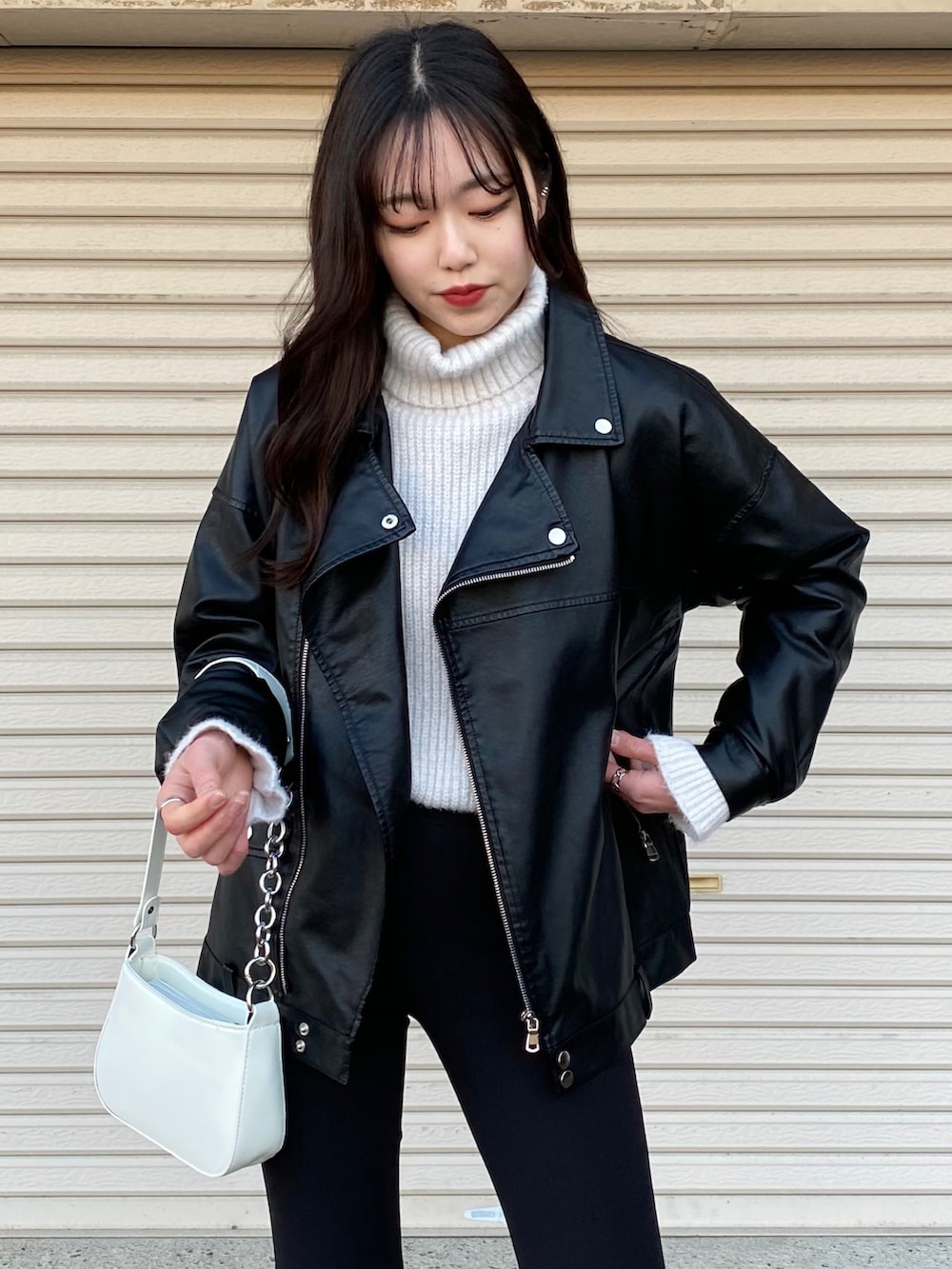 ブラック系のライダースジャケット、ホワイト系のニット/セーター、ホワイト系のスニーカーを着用したレディースの冬コーディネートの3枚目の写真