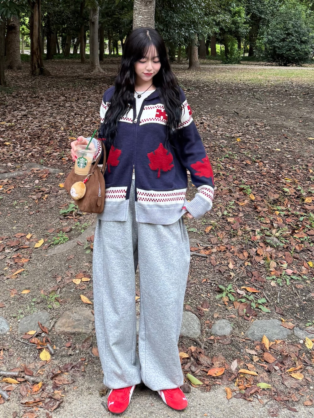 レッド系のスニーカー、ブルー系のニット/セーター、グレー系のスウェットパンツを着用したレディースの秋コーディネートの2枚目の写真