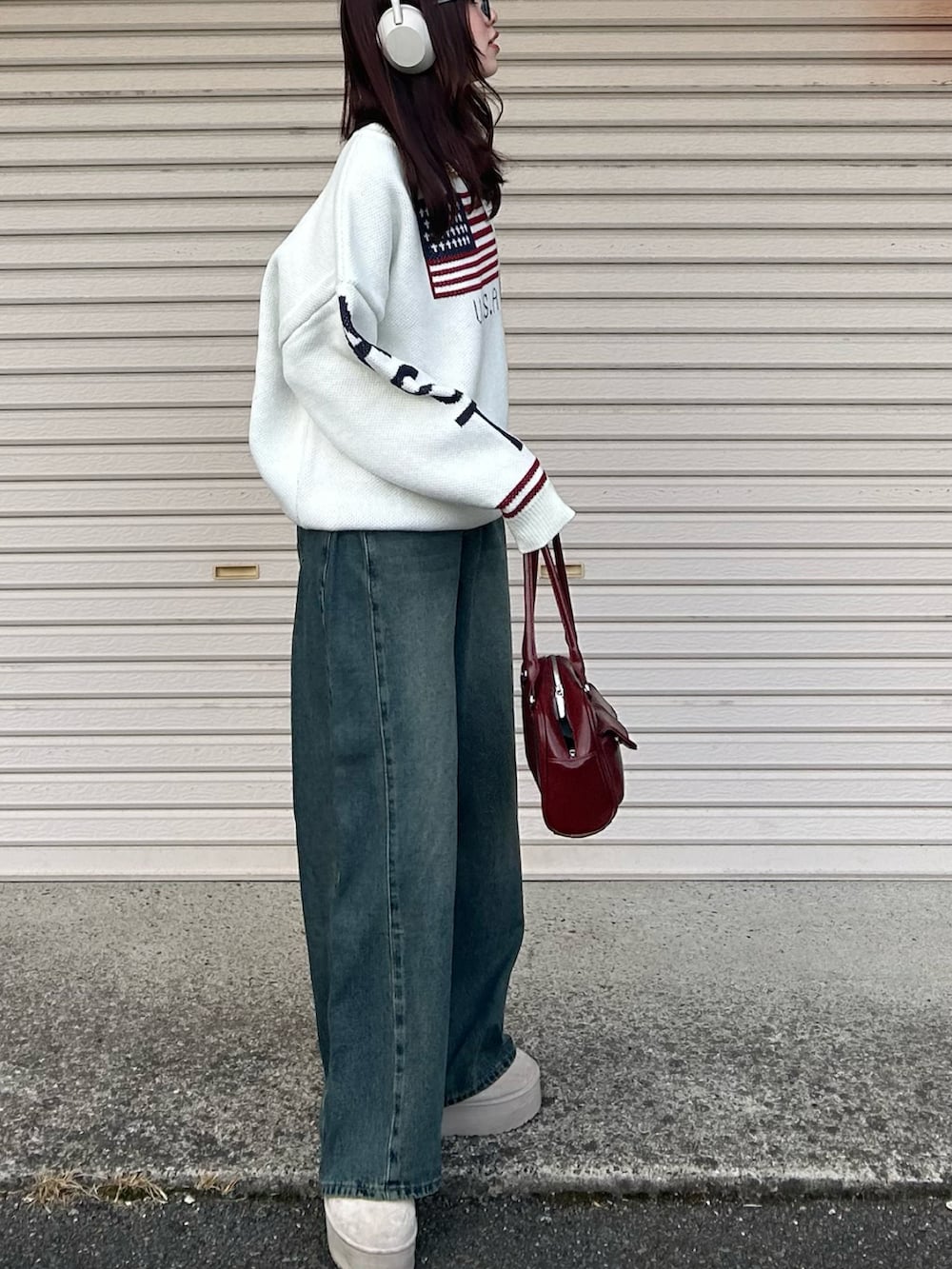 ブルー系のデニムパンツ、ホワイト系のニット/セーター、レッド系のハンドバッグを着用したレディースの冬コーディネートの3枚目の写真