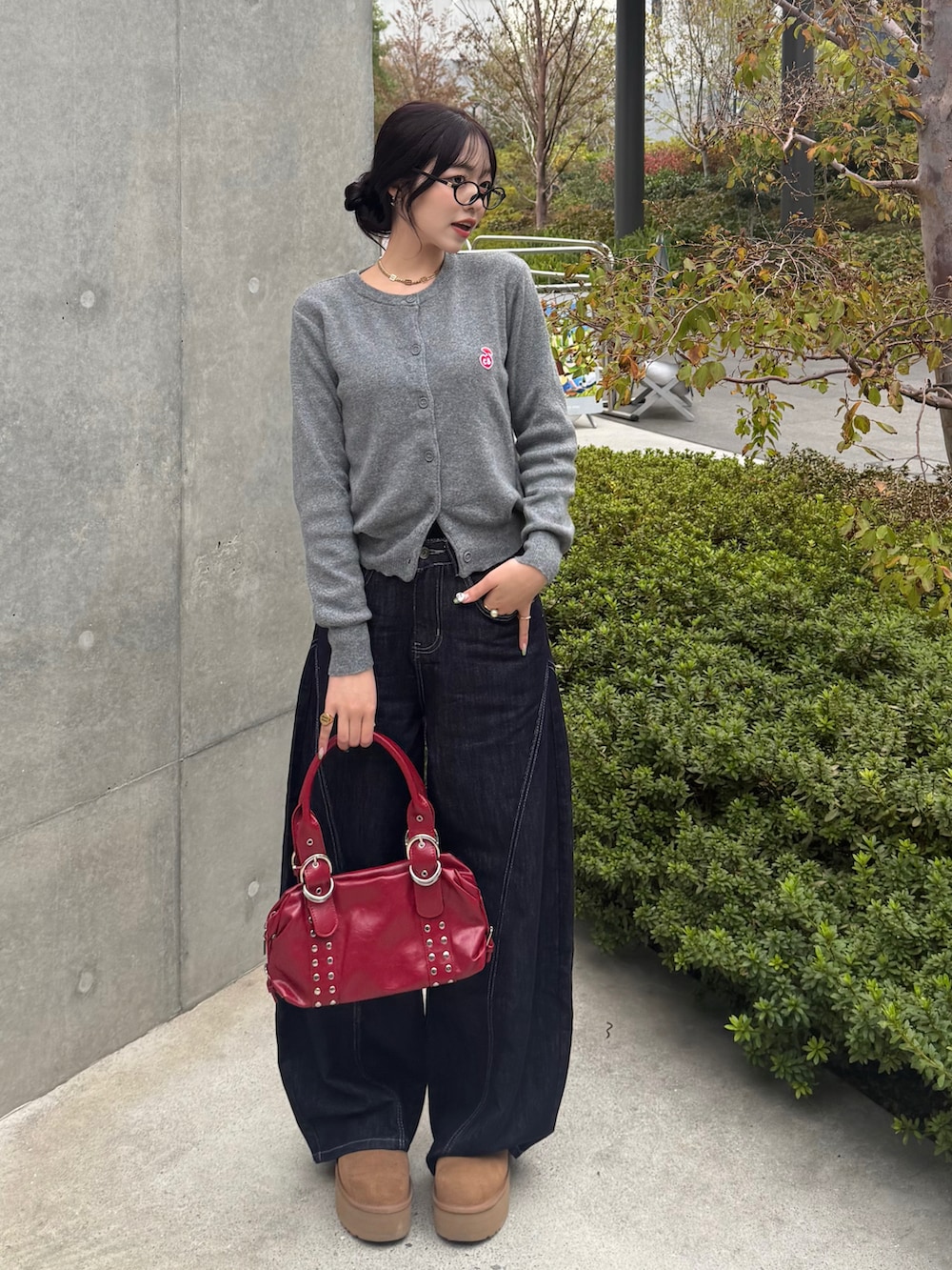 グレー系のカーディガン/ボレロ、ブルー系のデニムパンツ、レッド系のハンドバッグを着用したレディースの秋コーディネートの2枚目の写真