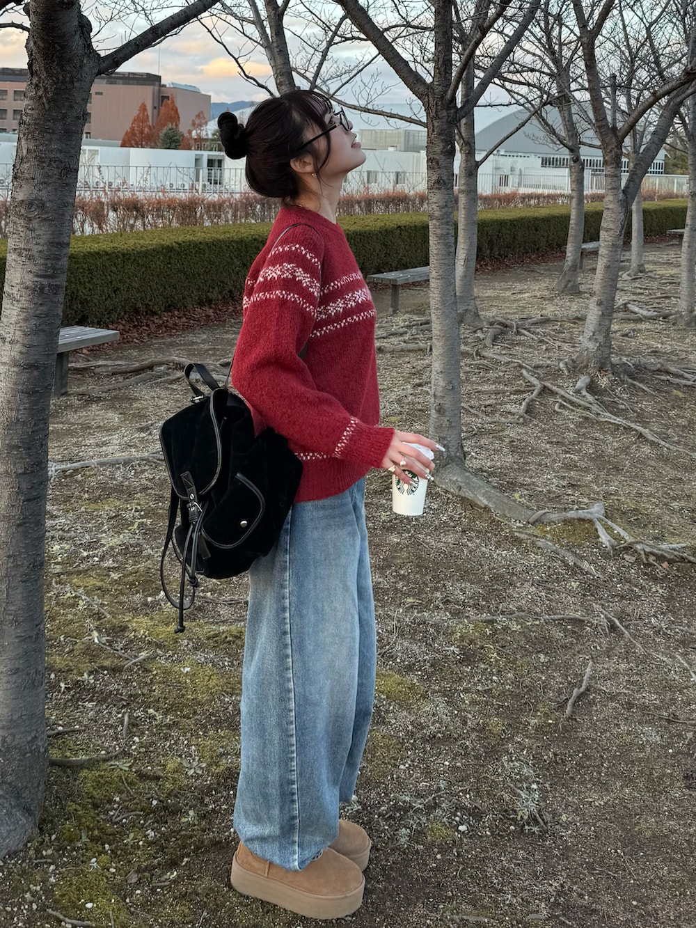 ブラック系のバックパック/リュック、ブラウン系のブーツ、レッド系のニット/セーターを着用したレディースの冬コーディネートの2枚目の写真
