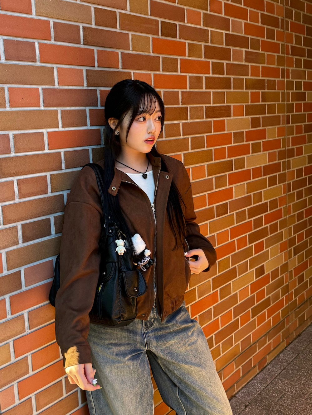 ブラウン系のスニーカー、ブラウン系のライダースジャケット、ブルー系のデニムパンツを着用したレディースの秋コーディネートの3枚目の写真