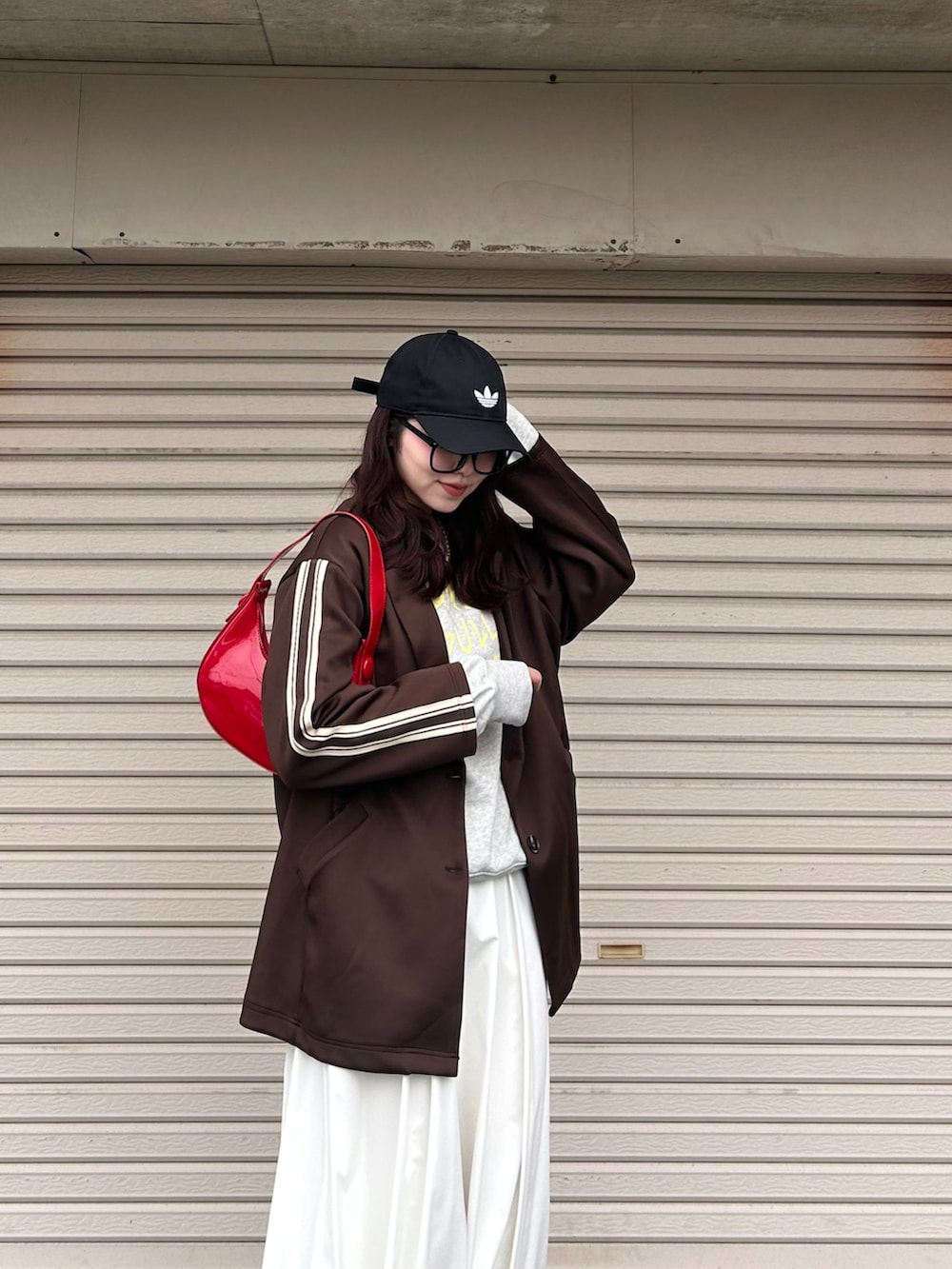 ブラウン系のその他アウター、レッド系のハンドバッグ、ホワイト系のスカートを着用したレディースの春コーディネートの2枚目の写真