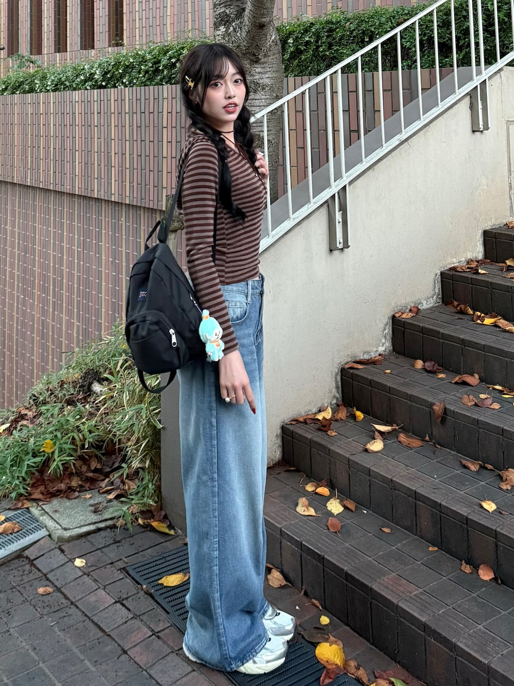 ブラウン系のパーカー、ブルー系のデニムパンツ、ブラック系のバックパック/リュックを着用したレディースの秋コーディネートの2枚目の写真