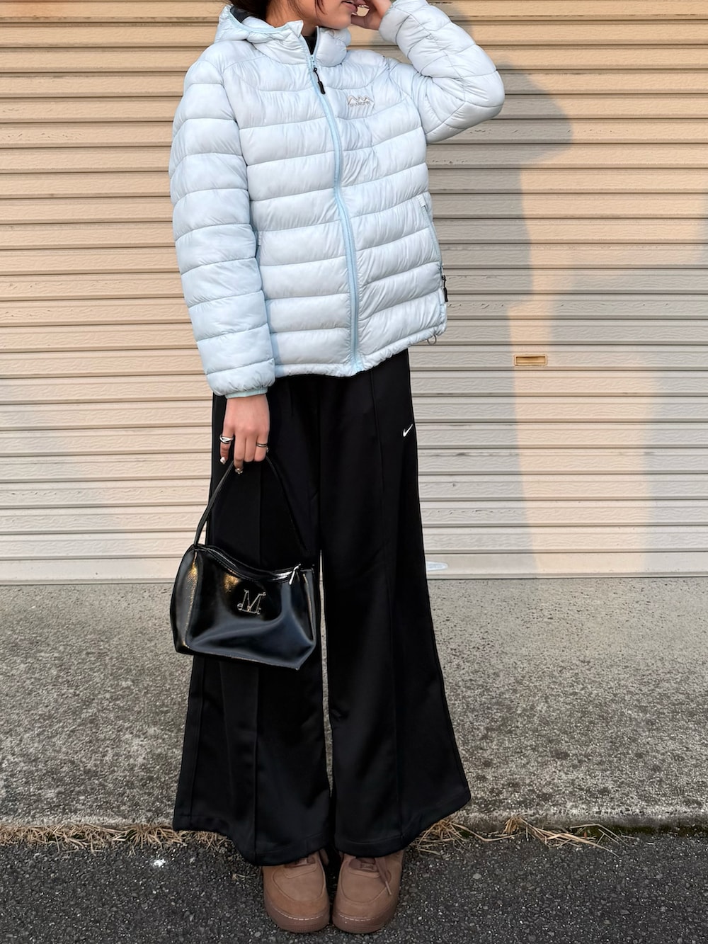 ブラック系のその他パンツ、ブラック系のショルダーバッグ、ブラウン系のスニーカーを着用したレディースの冬コーディネートの2枚目の写真