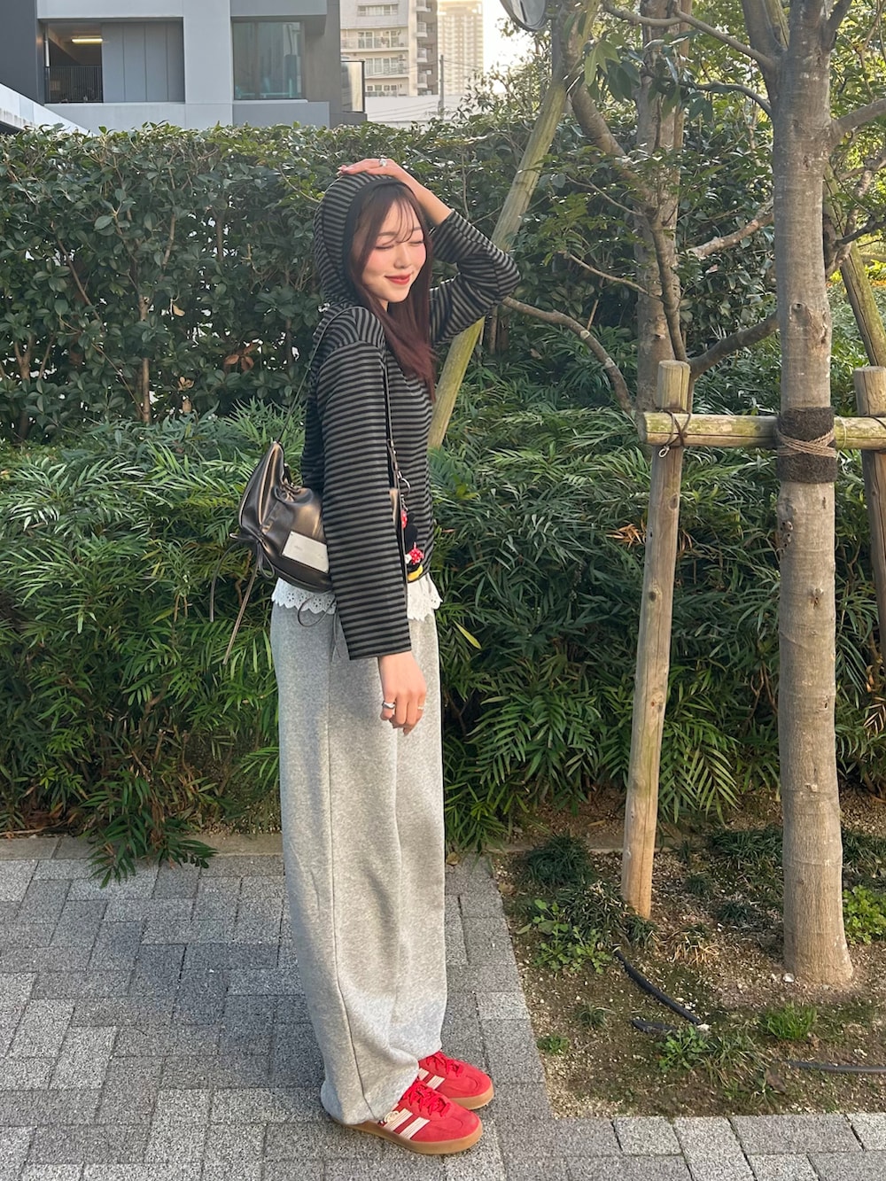 グレー系のスウェットパンツ、ブラック系のニット/セーター、レッド系のスニーカーを着用したレディースの春コーディネートの2枚目の写真