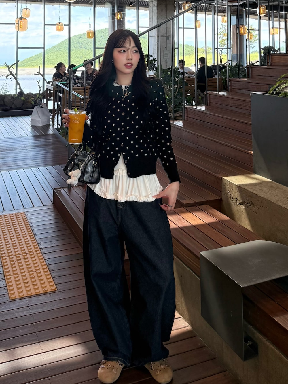 ブラック系のカーディガン/ボレロ、ブラック系のハンドバッグ、ブルー系のデニムパンツを着用したレディースの秋コーディネートの4枚目の写真