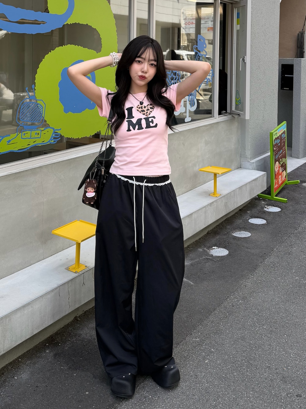 ピンク系のTシャツ/カットソー、ブラック系のパンツ、ブラック系のサンダルを着用したレディースの春コーディネートの2枚目の写真