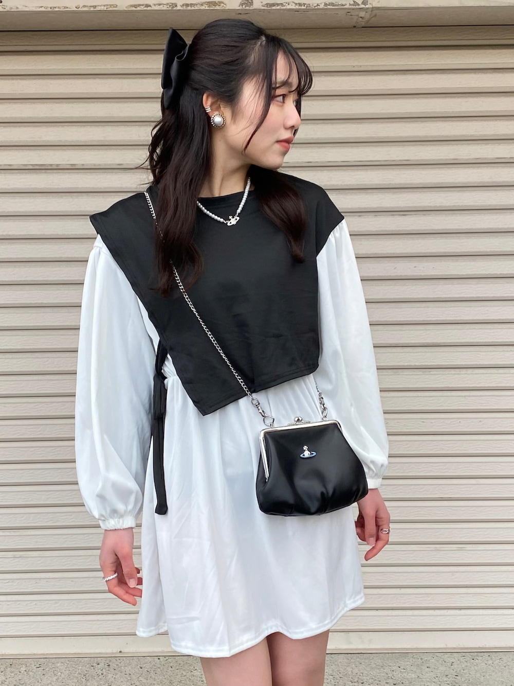 ホワイト系のワンピース、ブラック系のショルダーバッグ、ブラック系のブーツを着用したレディースの冬コーディネートの4枚目の写真