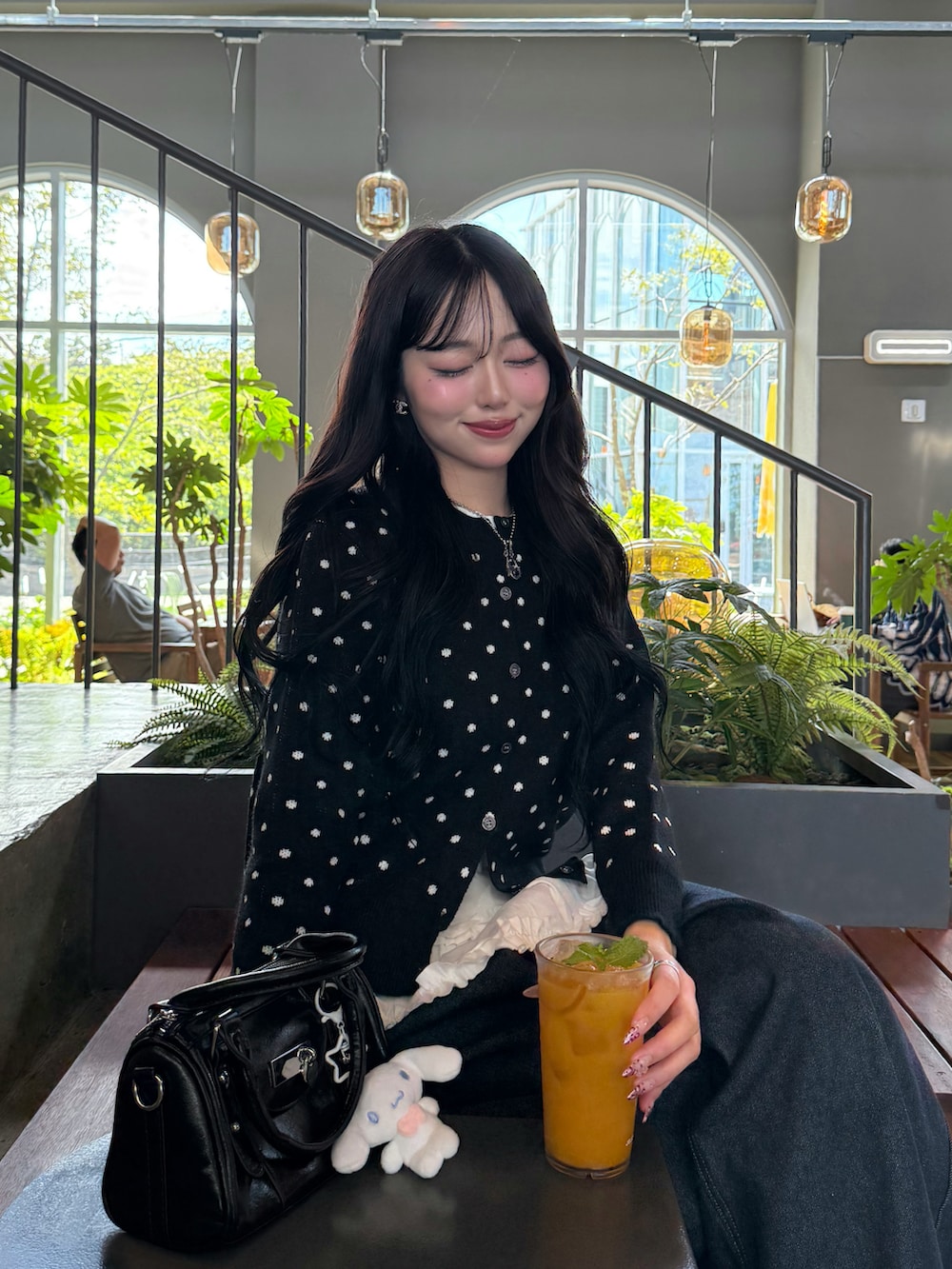 ブラック系のカーディガン/ボレロ、ブラック系のハンドバッグ、ブルー系のデニムパンツを着用したレディースの秋コーディネートの5枚目の写真