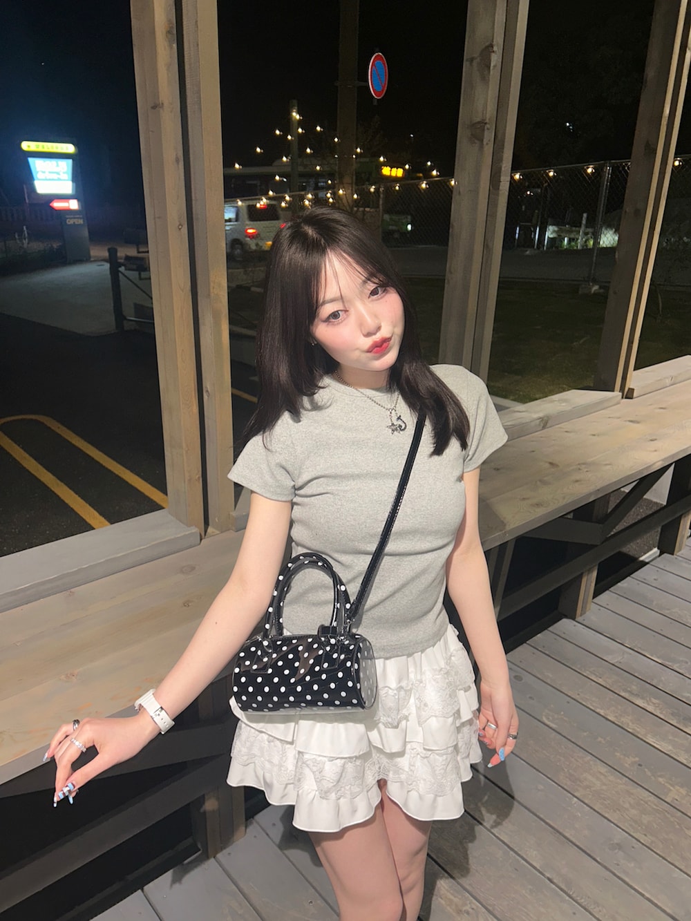 ブラック系のショルダーバッグ、ホワイト系のスカート、ホワイト系のスニーカーを着用したレディースの春コーディネートの3枚目の写真